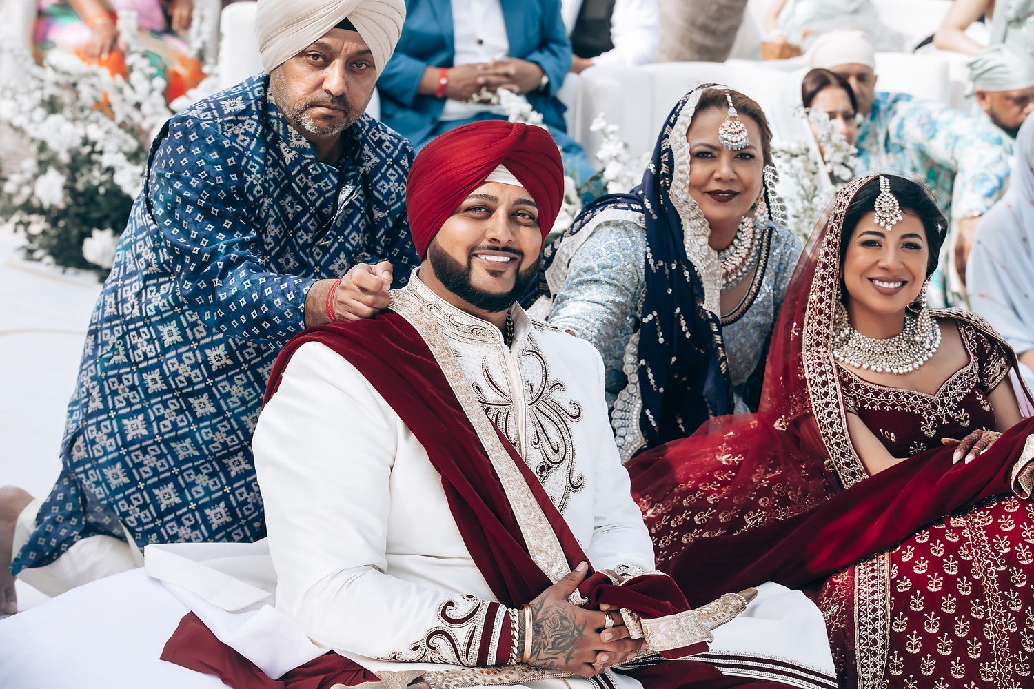 Festive wedding celebration with guests in traditional attire at beach venue.