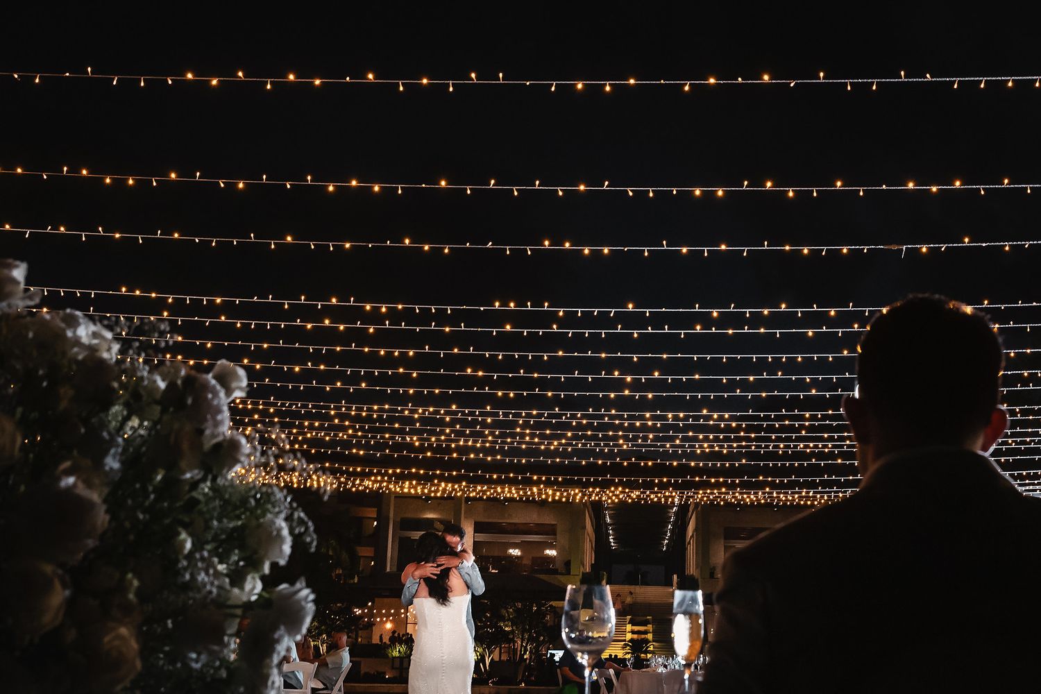 Wedding reception under canopy of string lights with guests celebrating at night.