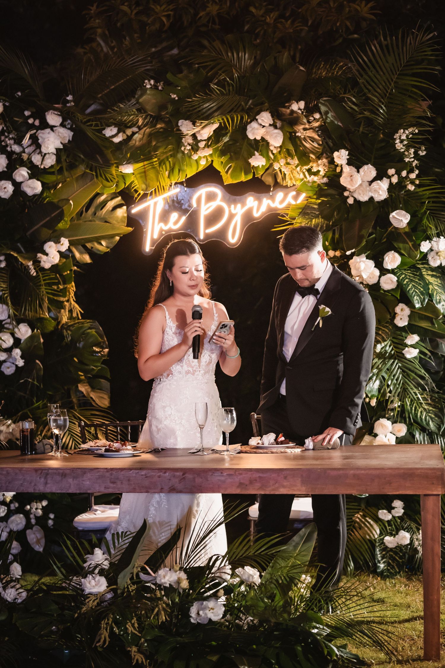 Couple shares emotional moments during wedding speeches at decorated outdoor reception.