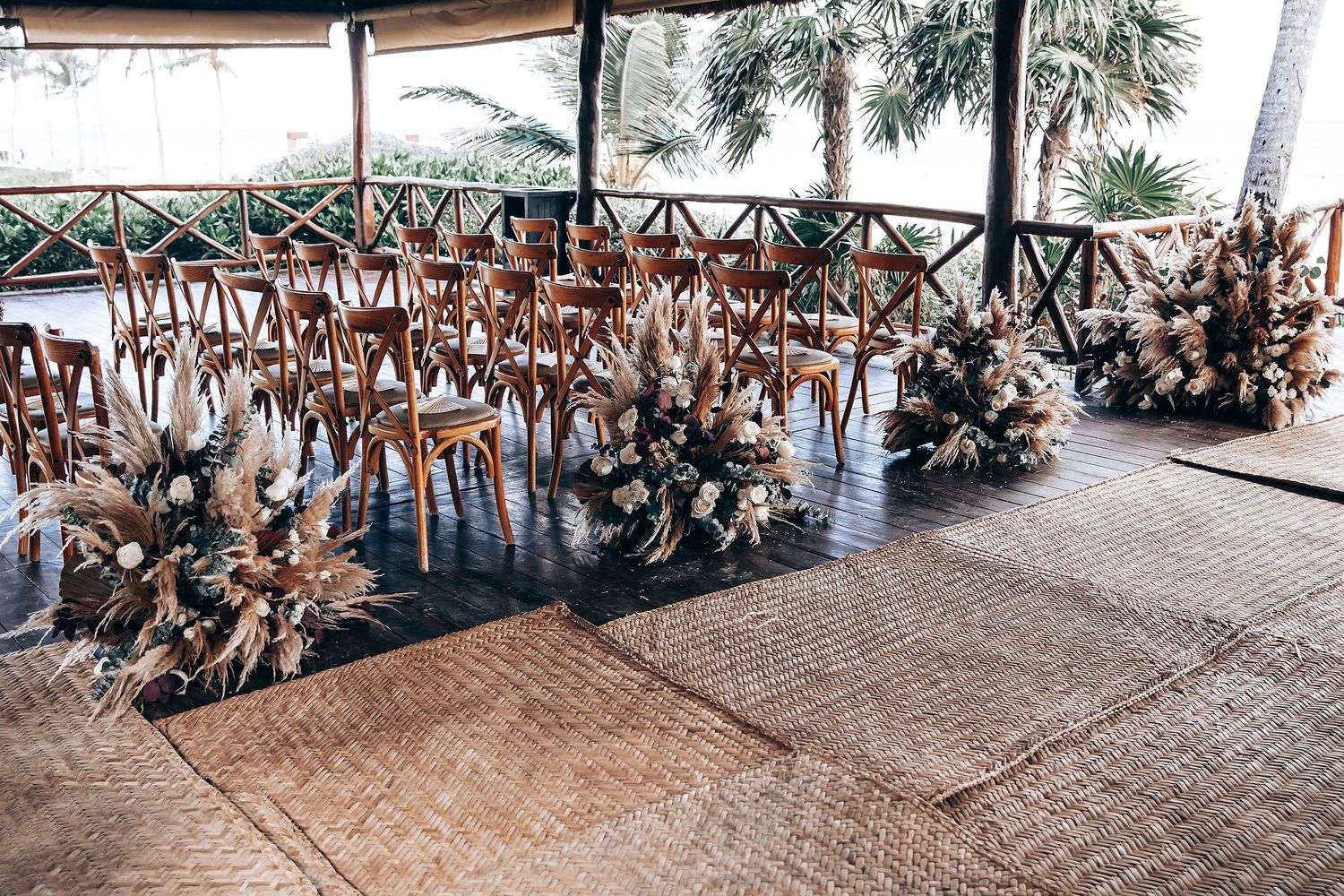 Rustic wooden chairs arranged in rows under a covered pavilion with ocean views.