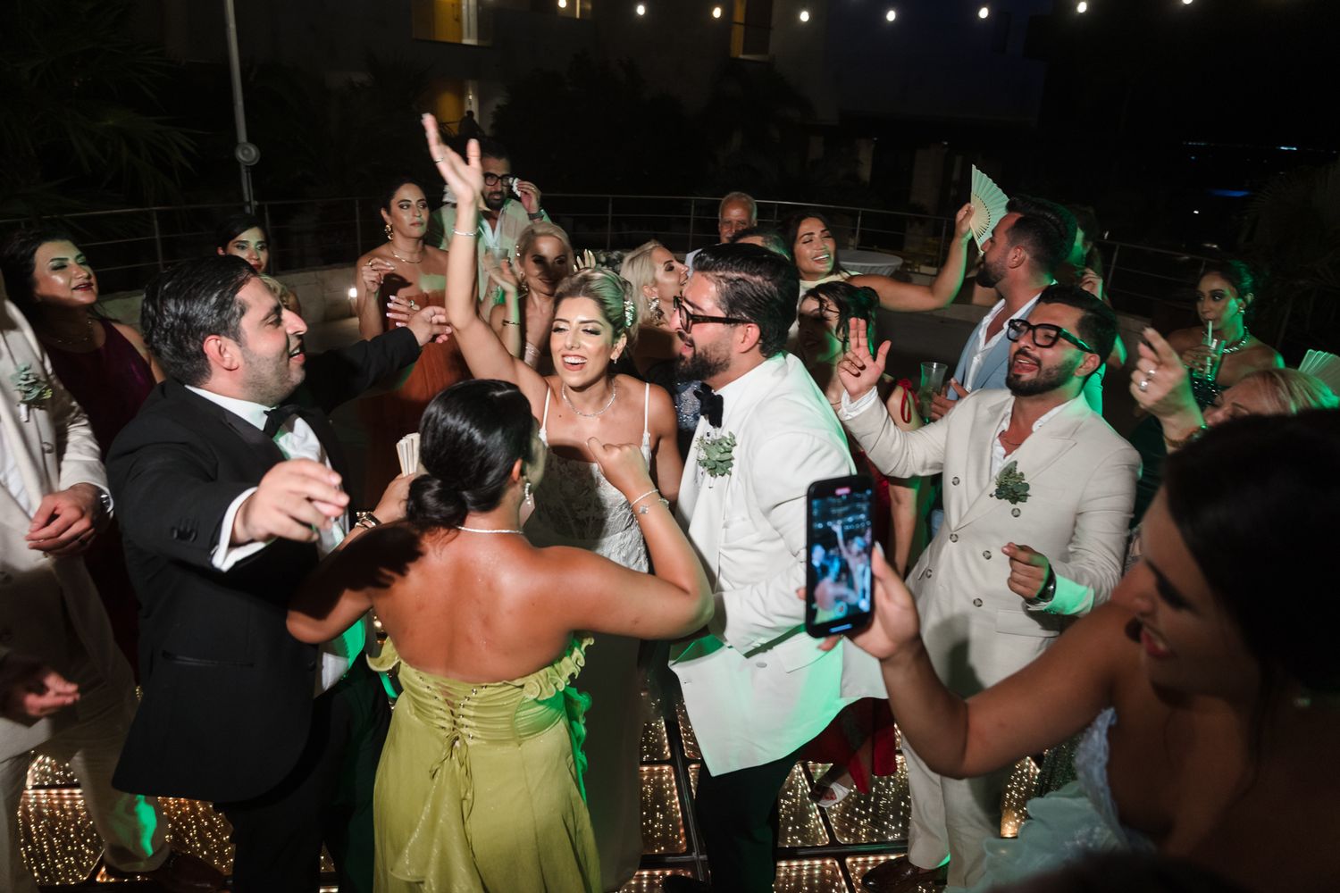Guests dancing and celebrating at lively outdoor evening wedding reception party.
