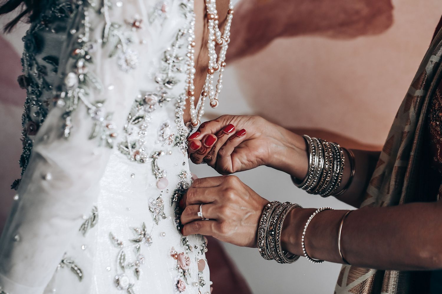 Close-up shot of hands adorned with silver bangles and bracelets against a white textured background.