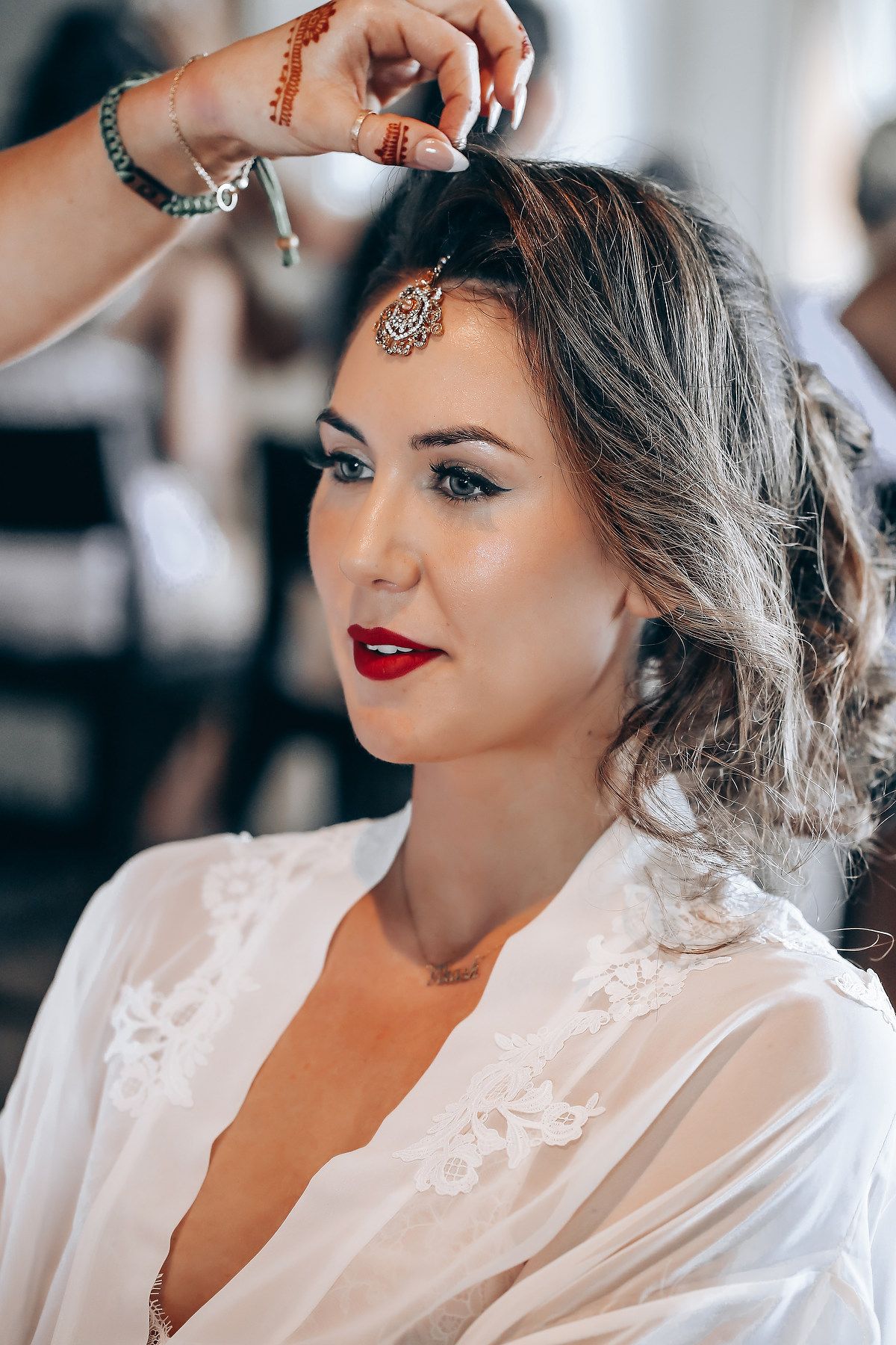 A sequence of close-up shots showing bridal makeup application and styling with red lipstick and elegant accessories.