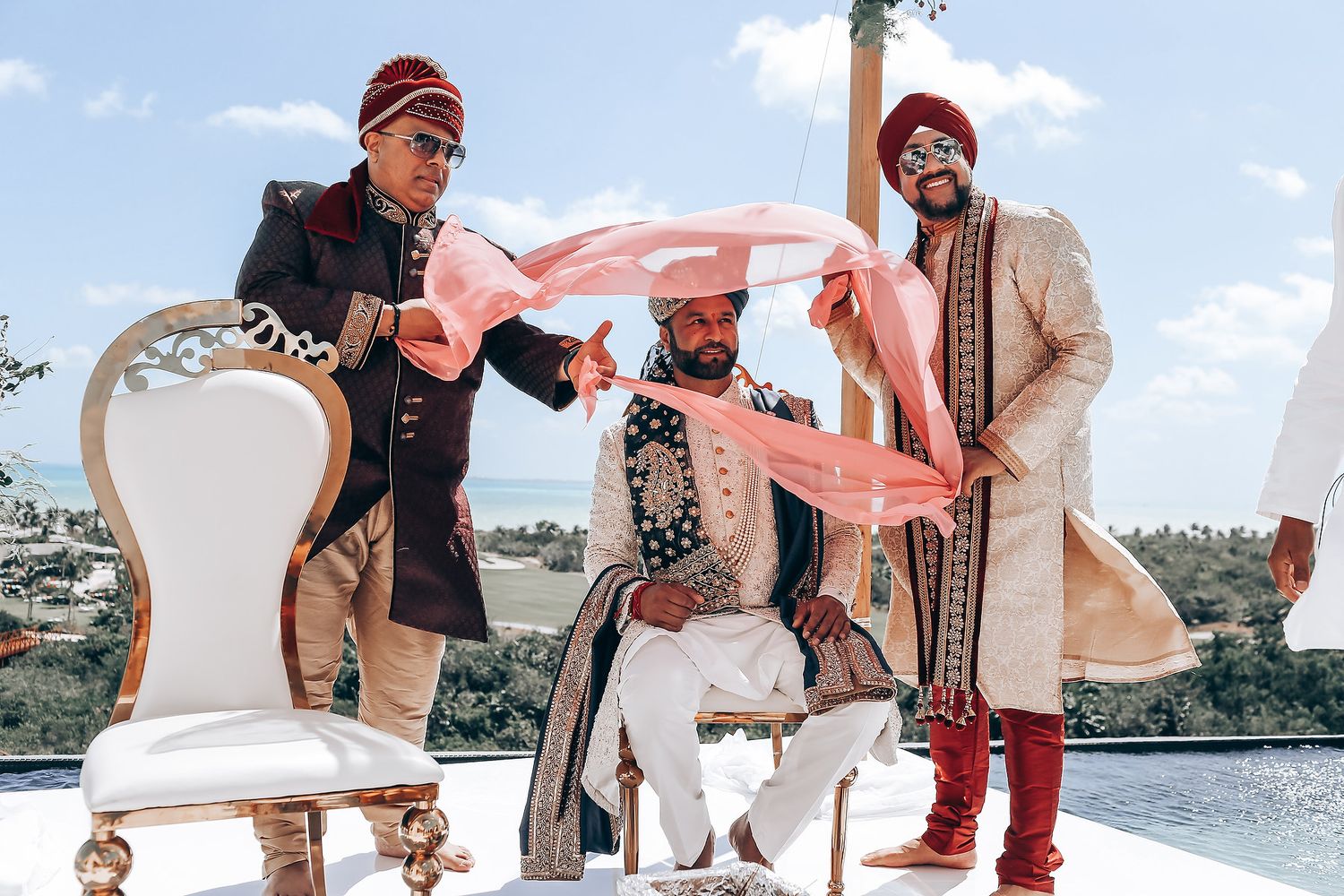 Guests enjoying a festive outdoor wedding ceremony with pink decor and natural scenery.