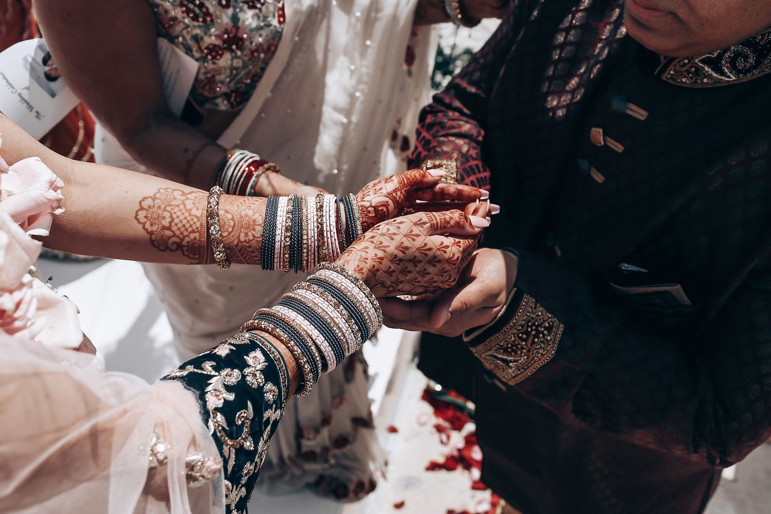 Close-up view of traditional henna mehndi designs being applied to hands during an Indian wedding ceremony.