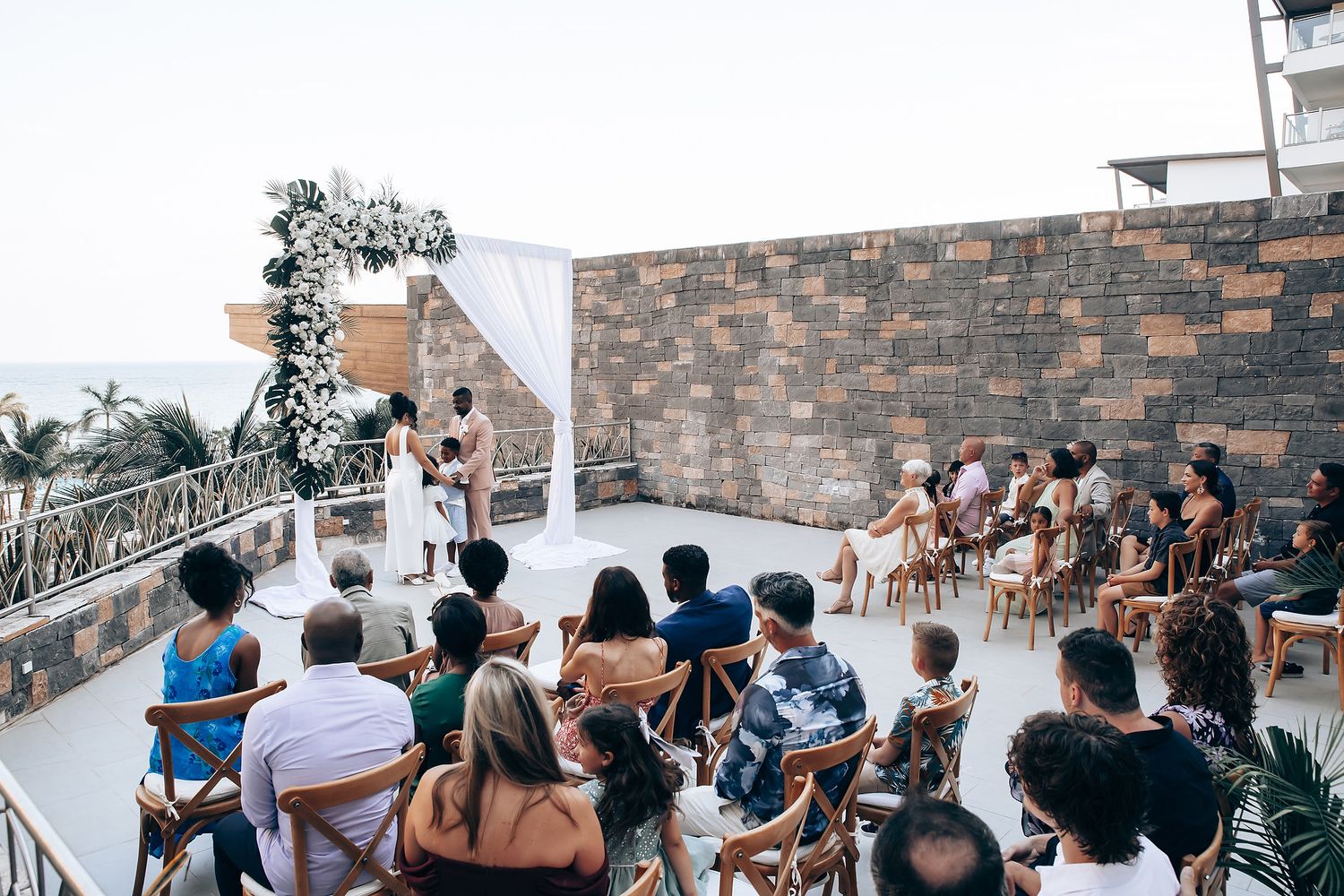 Wedding guests enjoying an outdoor celebration at a stone-walled venue.