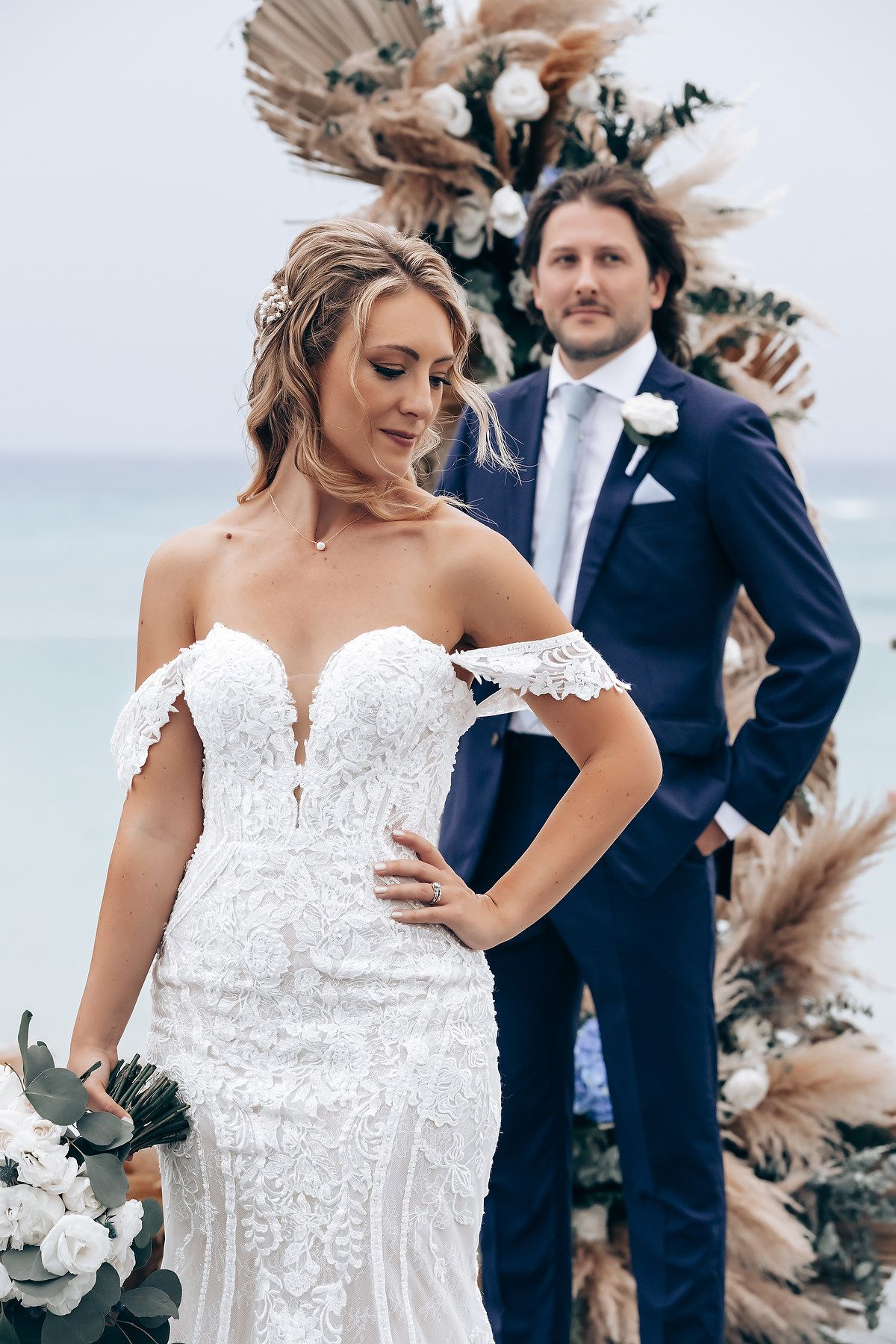 Elegant white wedding dress details with lace and off-shoulder design against a natural backdrop.