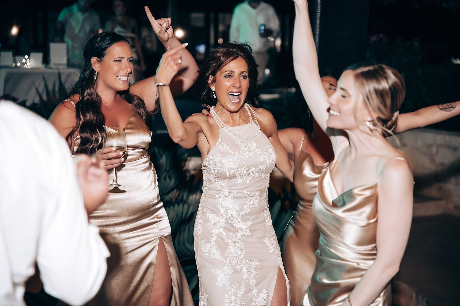 Wedding guests dancing and celebrating on a dark dance floor with party lights.