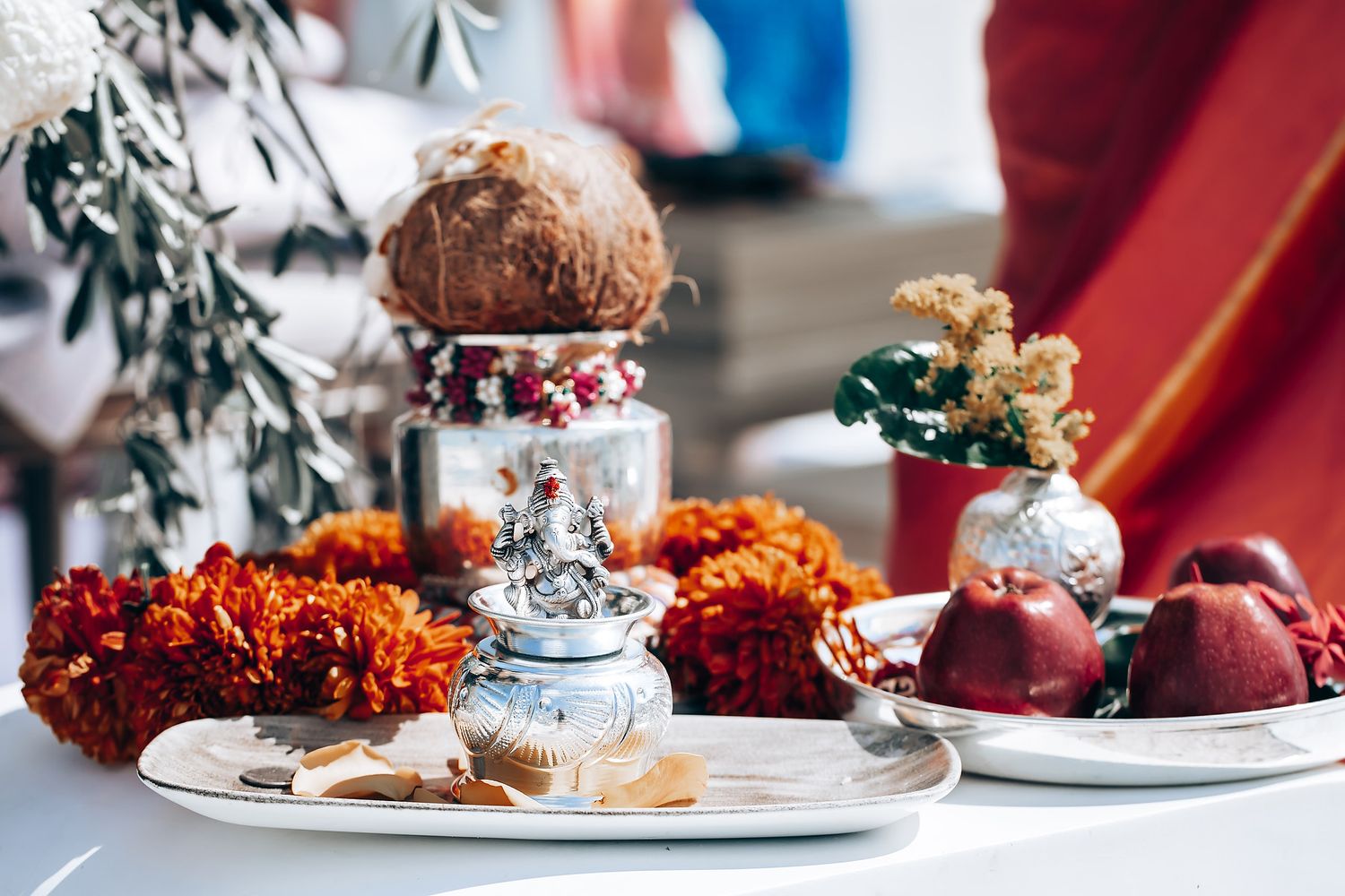 Elegant table settings with orange marigold garlands and silver decorations at an Indian wedding reception.