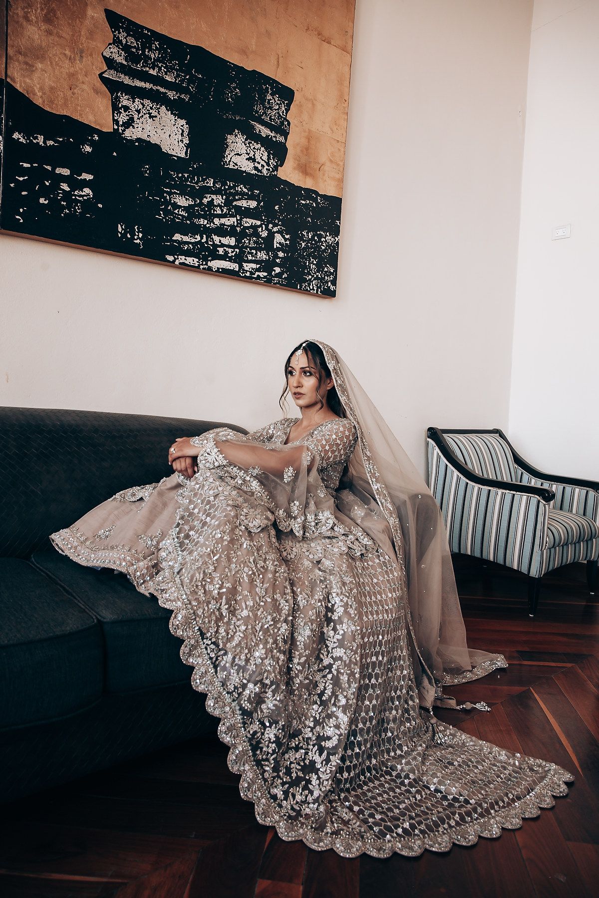 Elegant bridal gown with beaded details and lace trim displayed on hardwood floor.