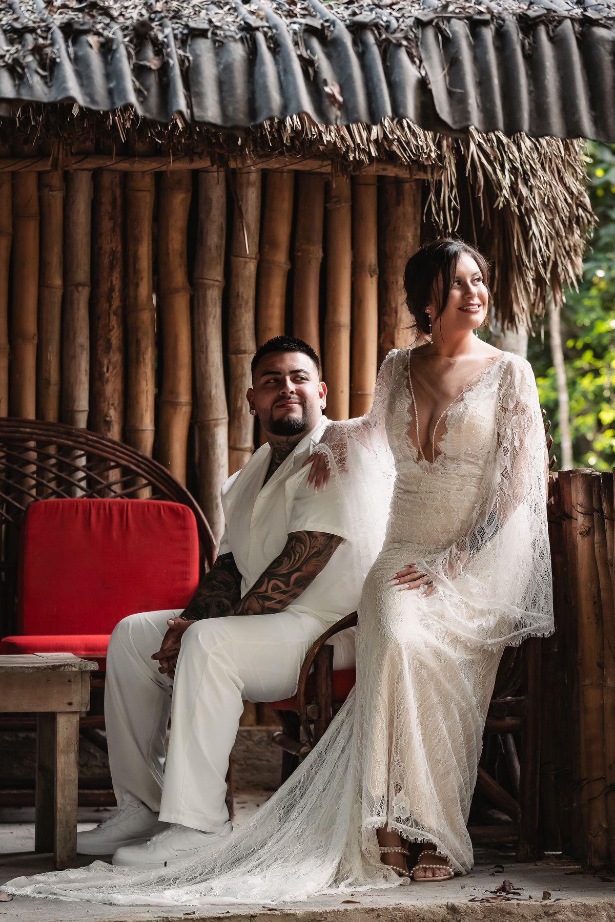 Elegant couple's portrait session in a traditional bamboo hut with red accents.