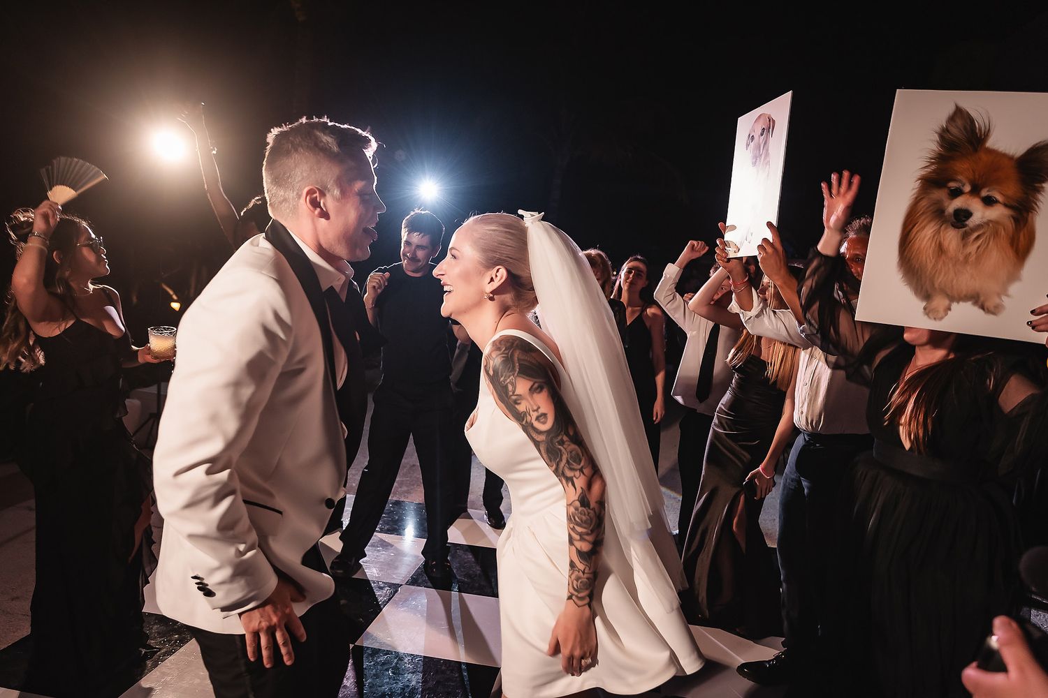 Wedding reception dance floor with guests celebrating under dramatic lighting.