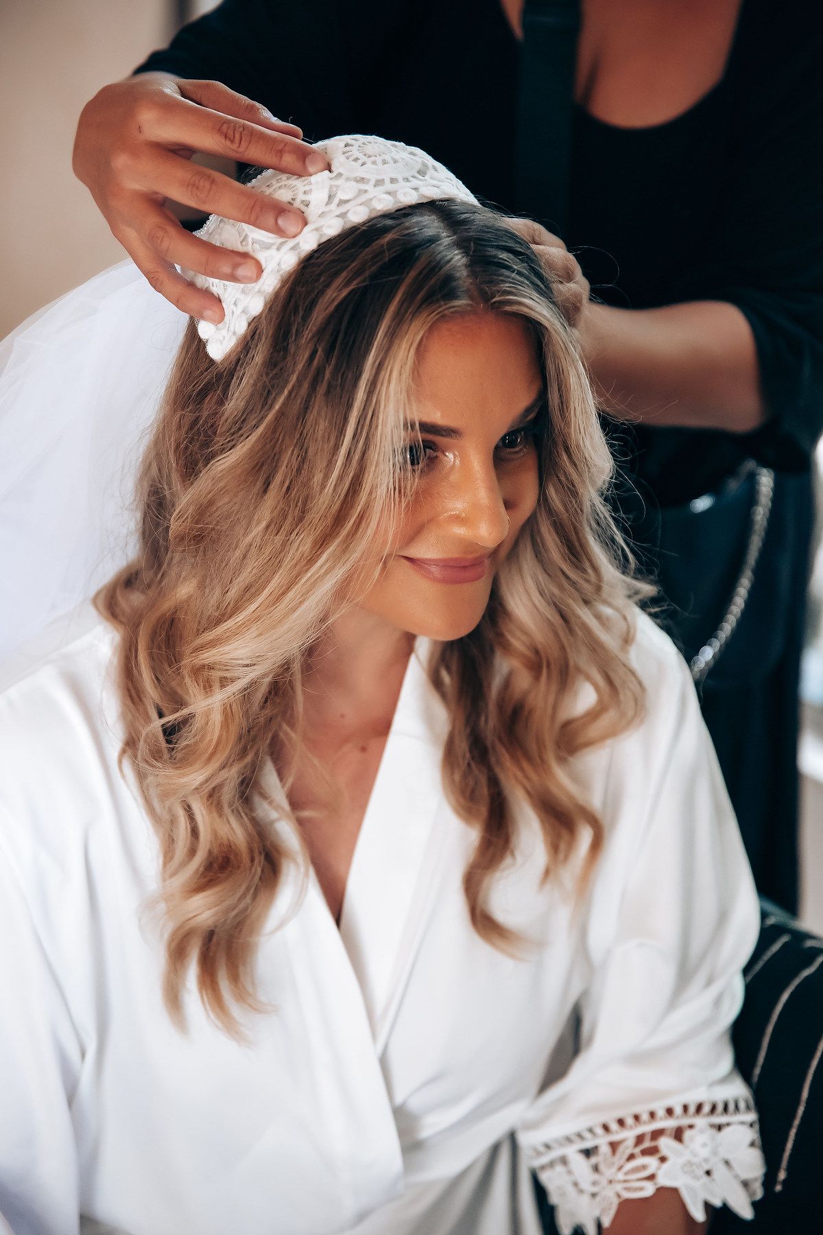 A person in a white robe getting their hair styled during wedding preparations.