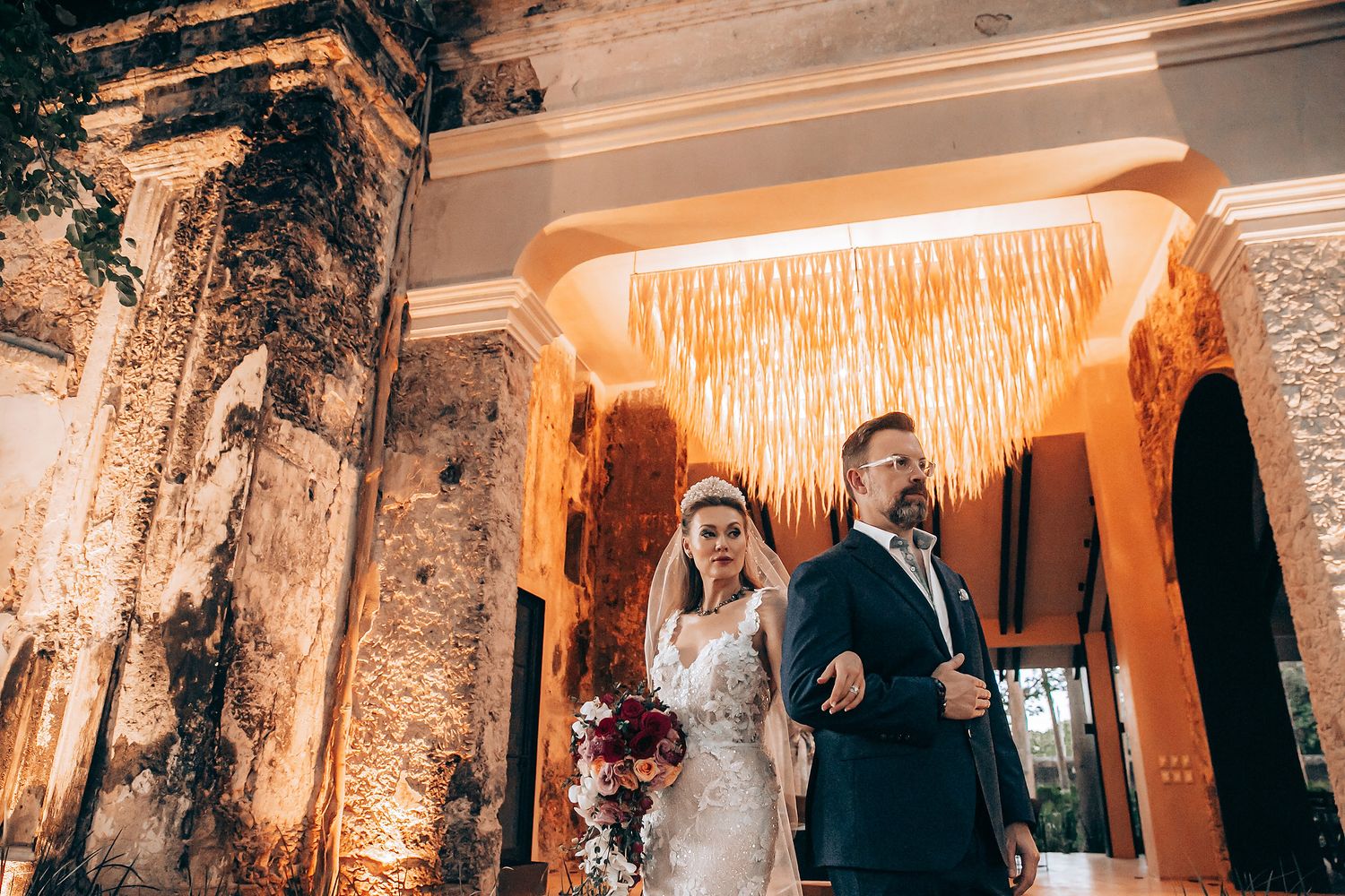Wedding reception venue decorated with warm lighting and crystal chandeliers creating romantic ambiance.