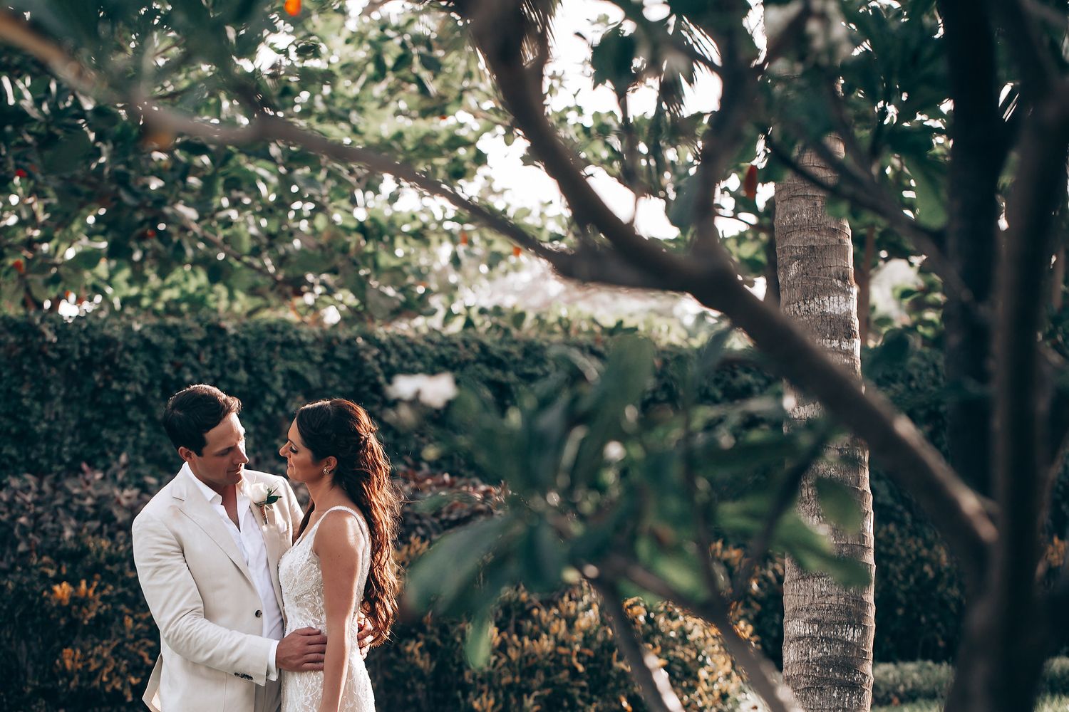 Intimate wedding portraits captured in a sunlit garden with white attire.