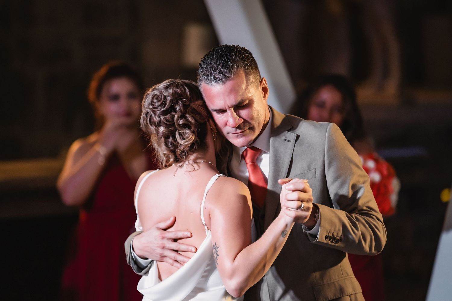 Intimate first dance moment captured in dramatic lighting at wedding reception.