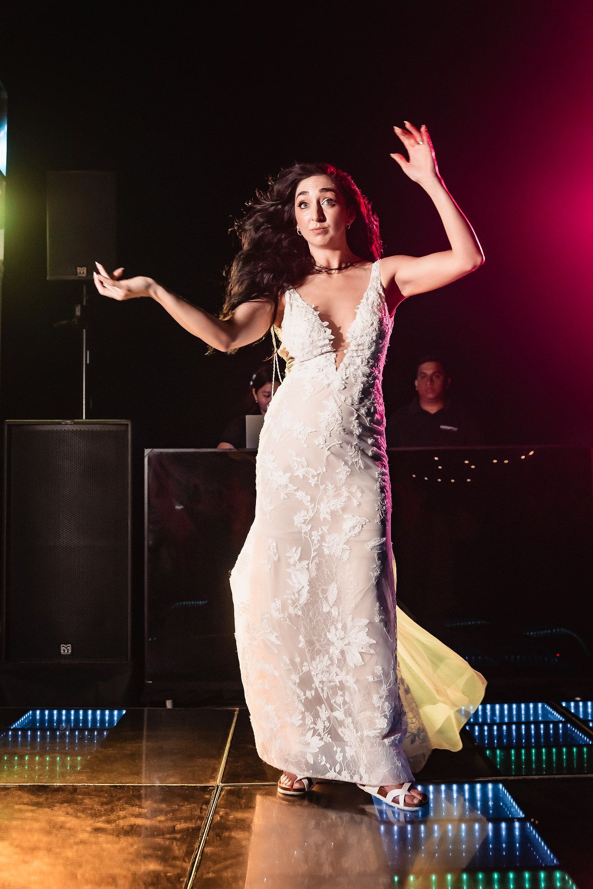 A bride dancing on an illuminated dance floor during an evening wedding reception.