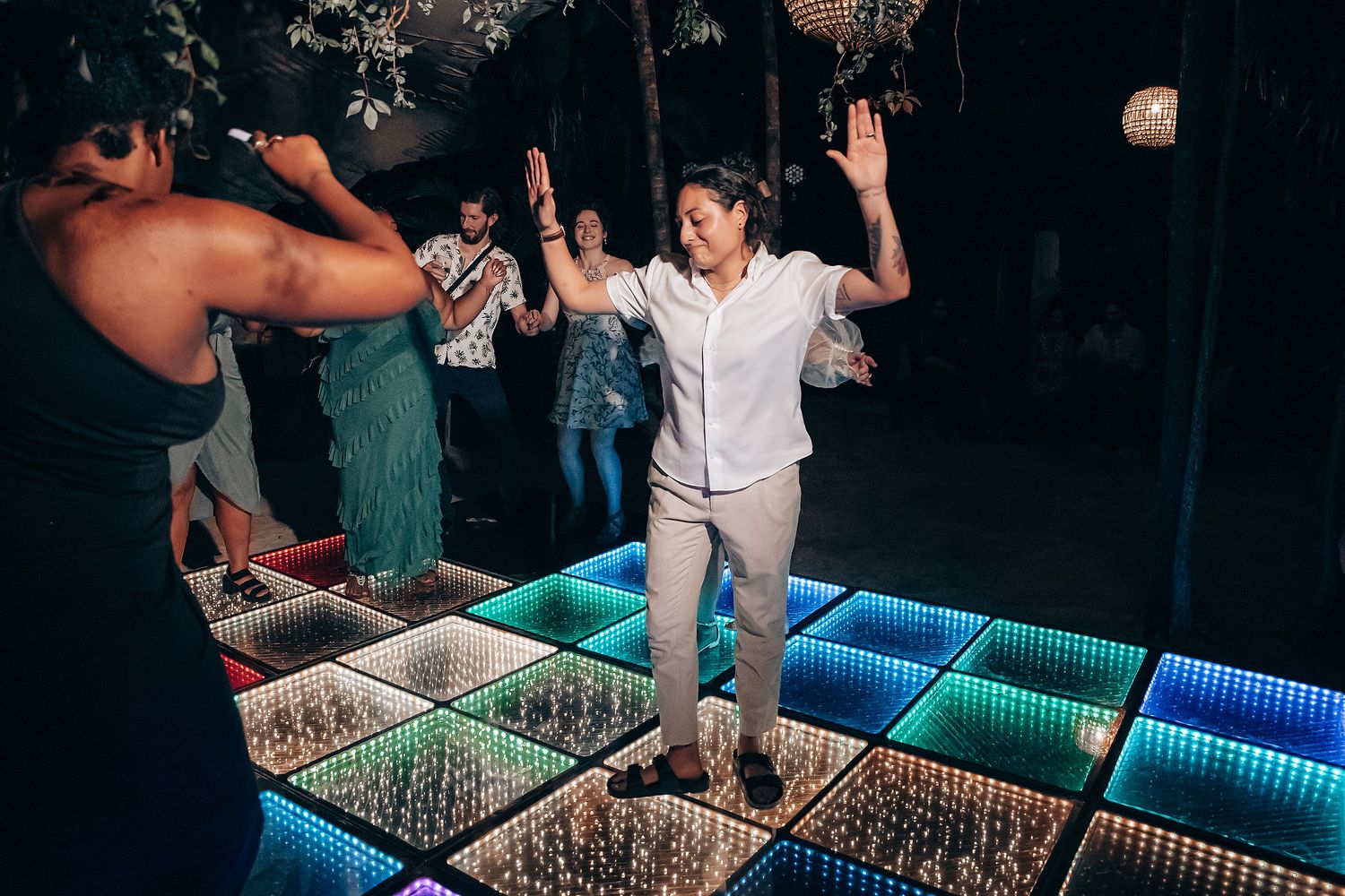People dancing on an illuminated LED dance floor with colorful lights creating a vibrant nightclub atmosphere.