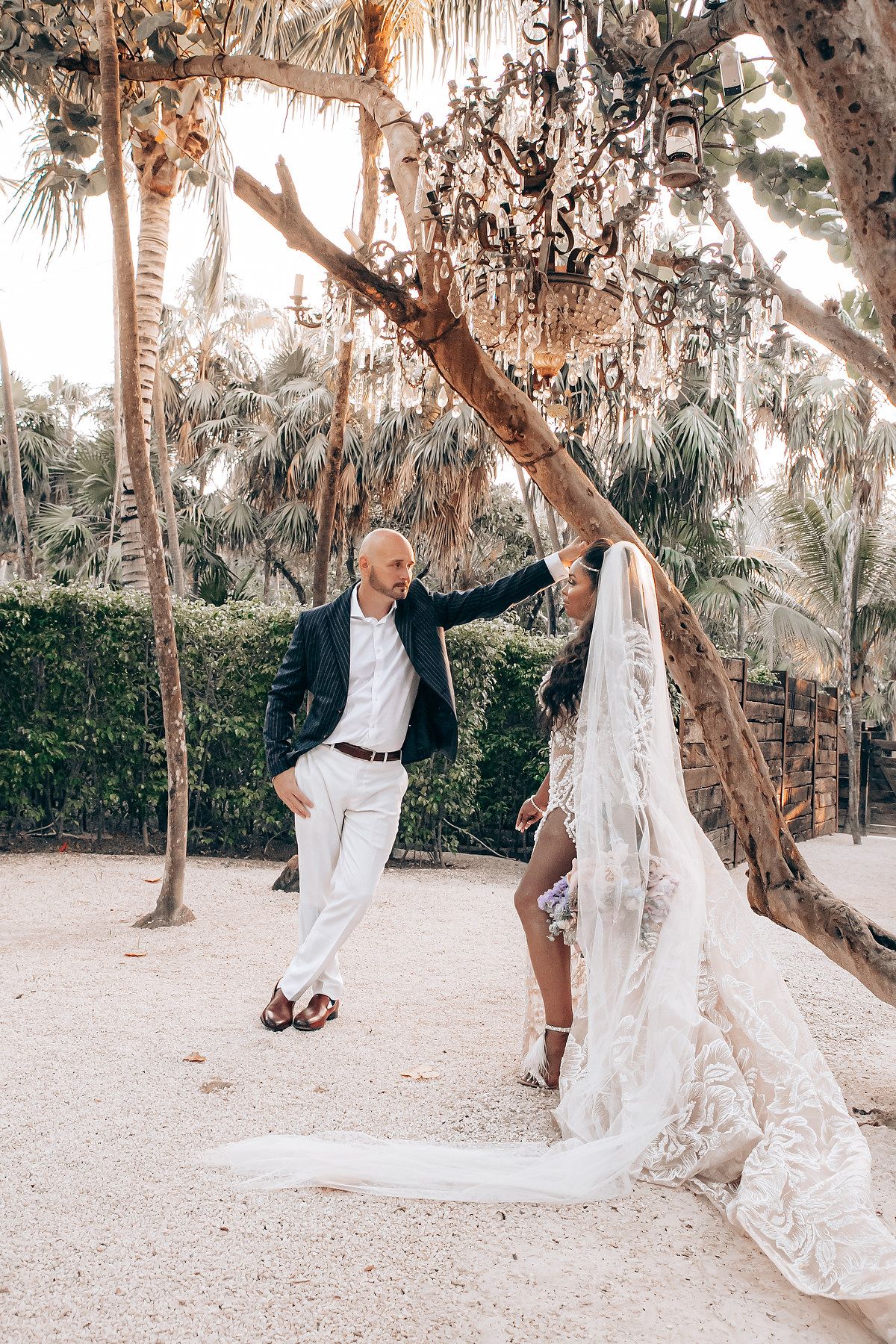 Playful wedding couple swings on a tree branch at a romantic beach location with Spanish moss hanging overhead.