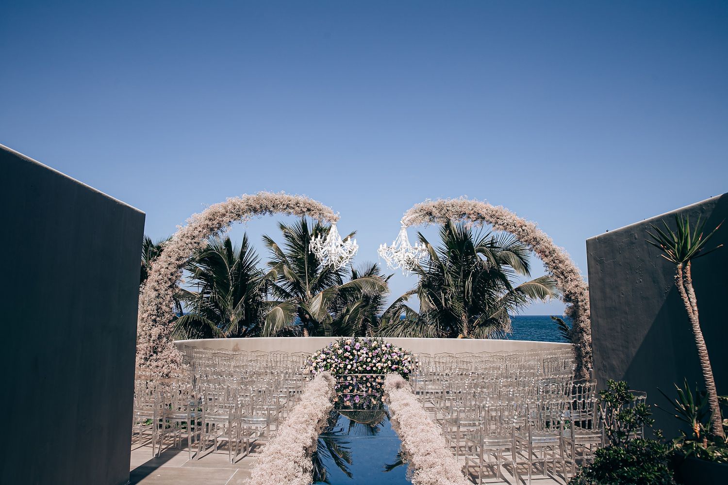 A curved stone archway entrance with palm trees and blue sky creates a tropical resort atmosphere.
