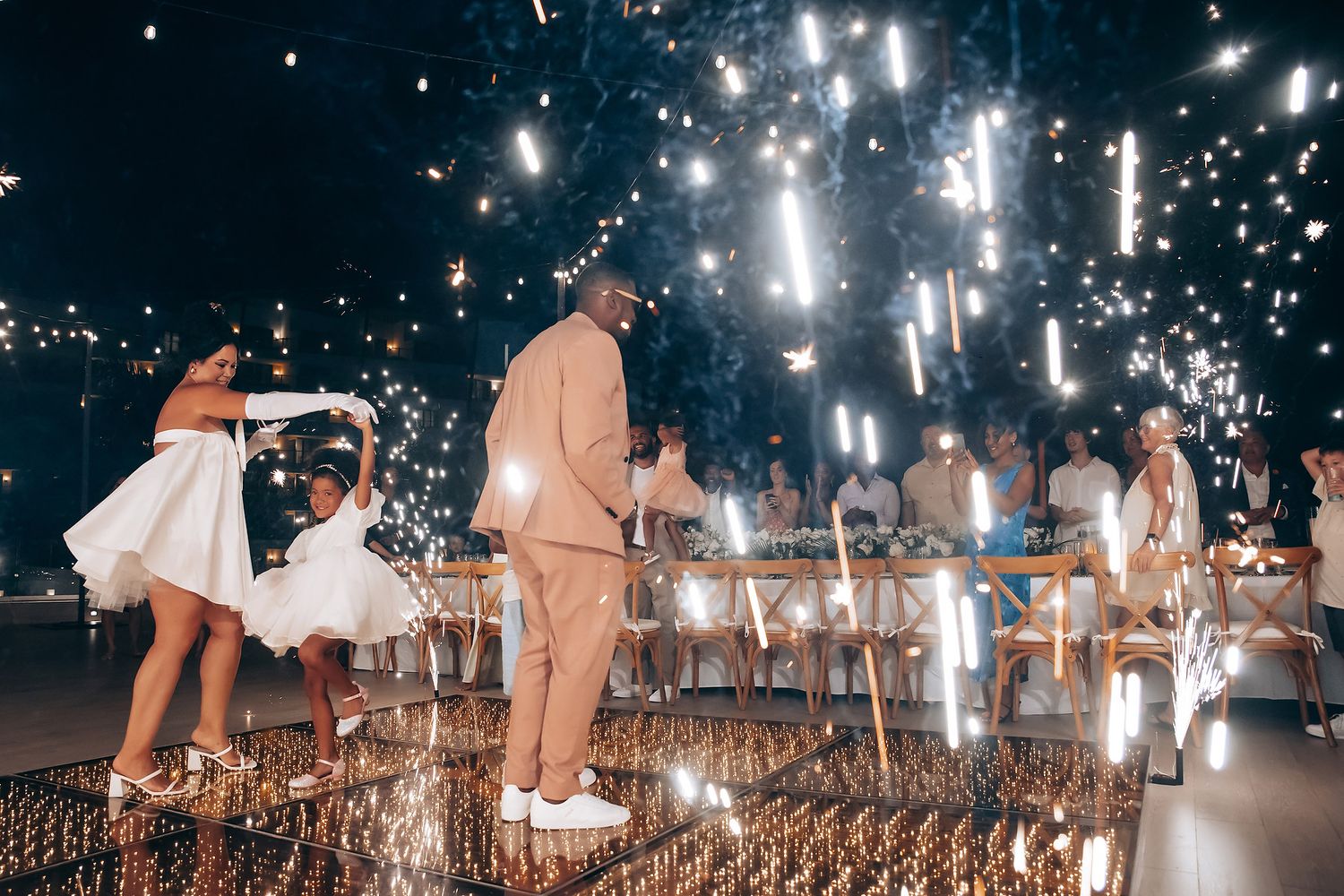 Glowing sparklers illuminate a nighttime celebration scene.