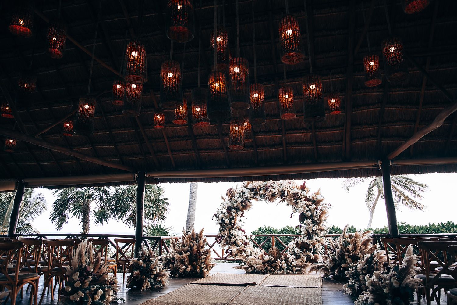 Tropical wedding venue with thatched roof and string lights creating a romantic ambiance.