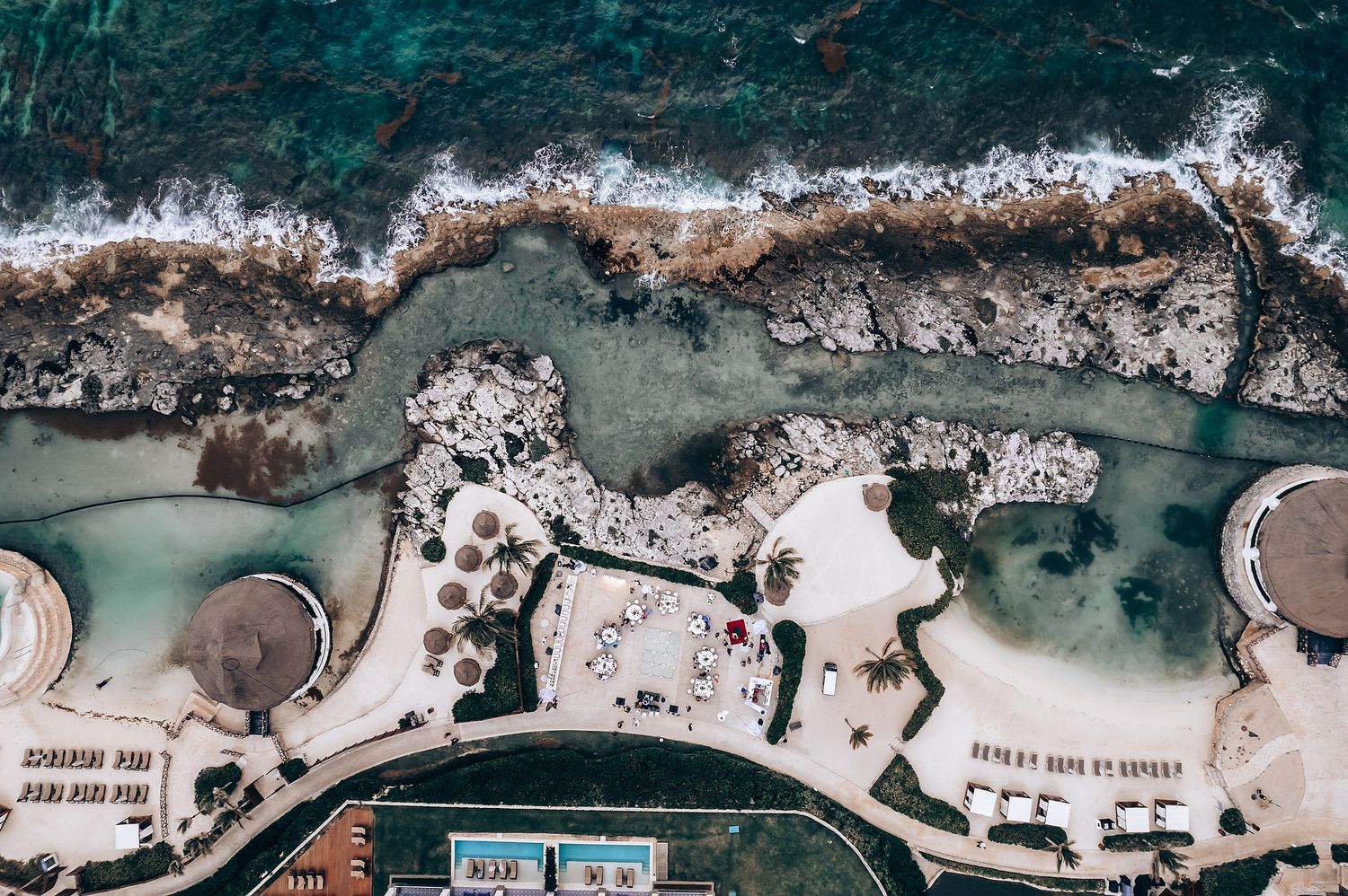 Aerial view of a rocky coastline with turquoise waters and white surf breaking against the shore.