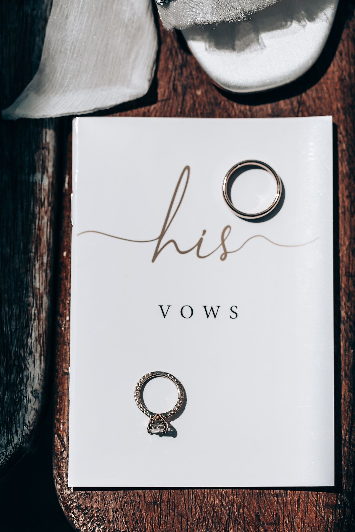 Wedding rings and vows cards displayed on a dark wooden surface for a romantic ceremony.