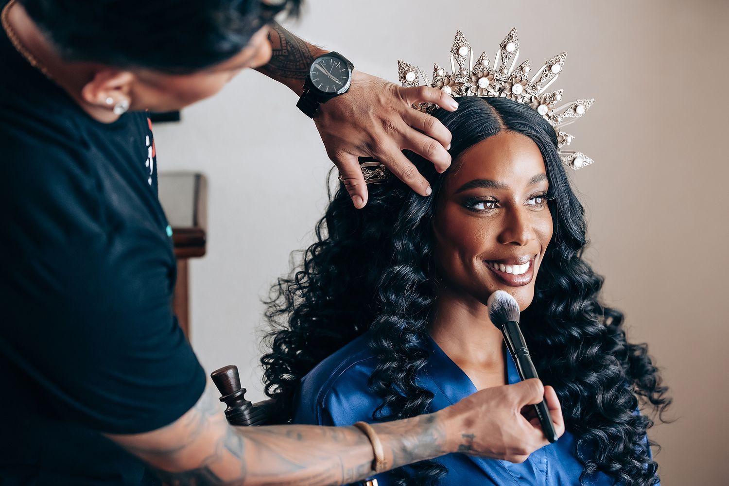 Elegant crystal tiara being placed on styled curls during wedding preparation.