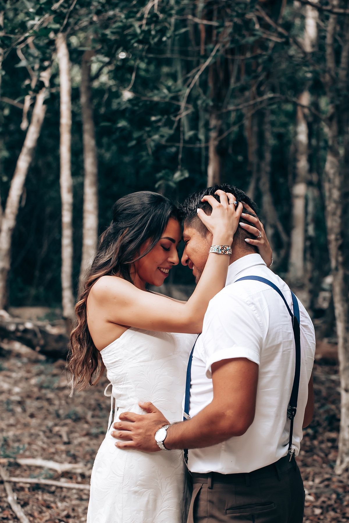 A romantic couple shares intimate embraces in a series of candid moments captured in a wooded forest setting.