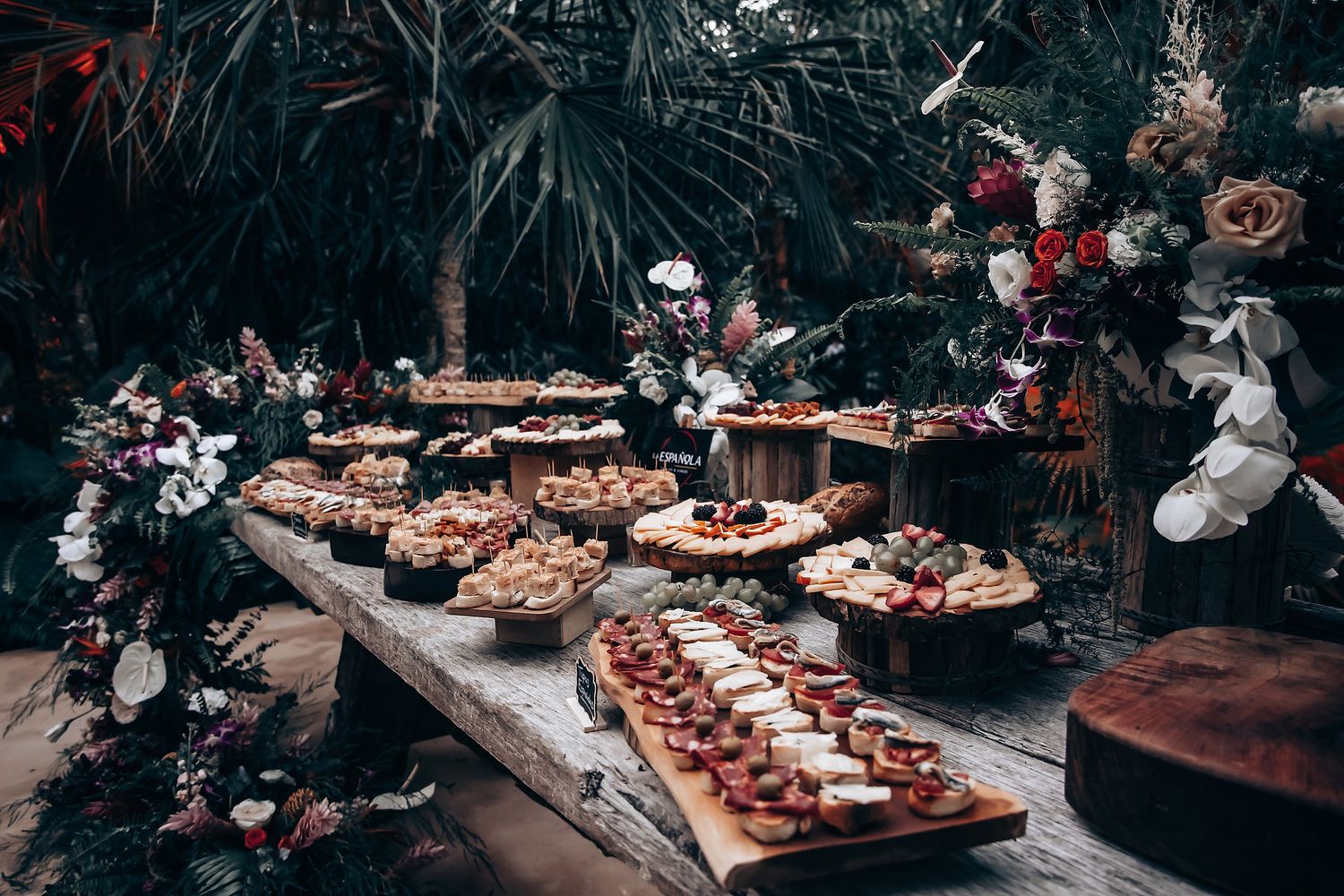 Elegant wedding reception tables decorated with floral arrangements and food platters at an outdoor venue.