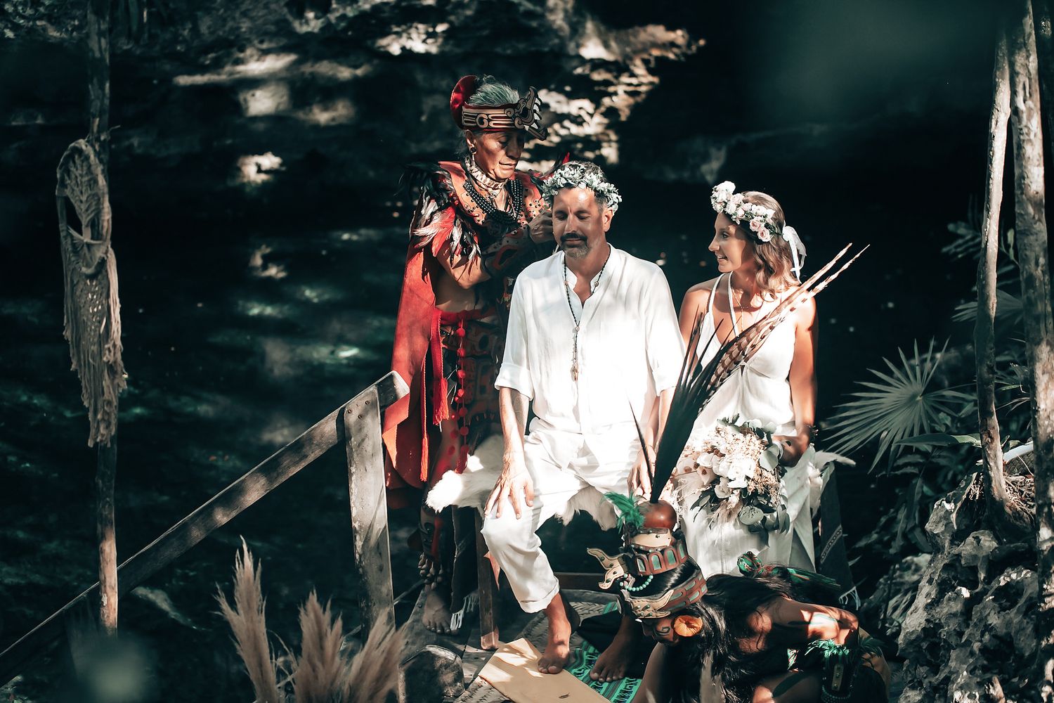 A group of people dressed in traditional indigenous attire walking through a lush, forested environment.