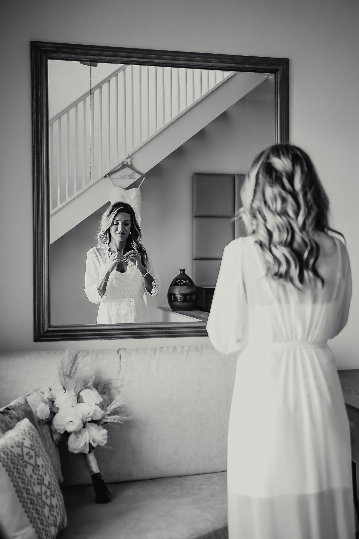 A woman in a white dress looking at herself in a mirror.