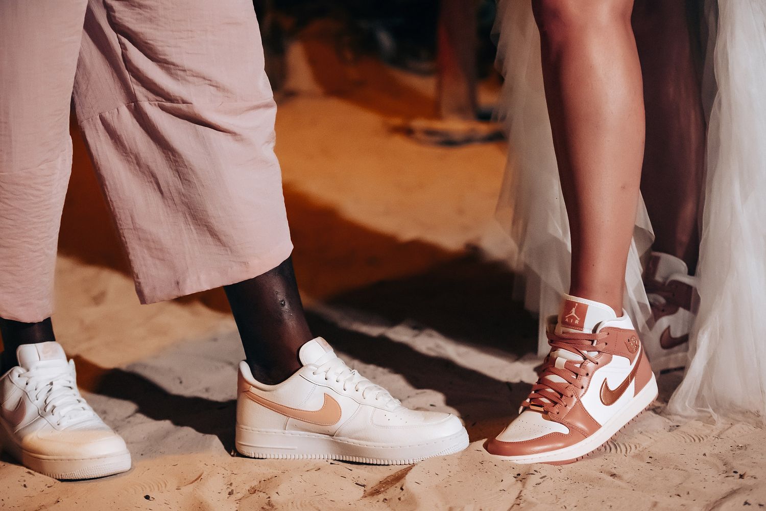 The image shows a bride and groom walking together on a beach, with the ocean in the background.
