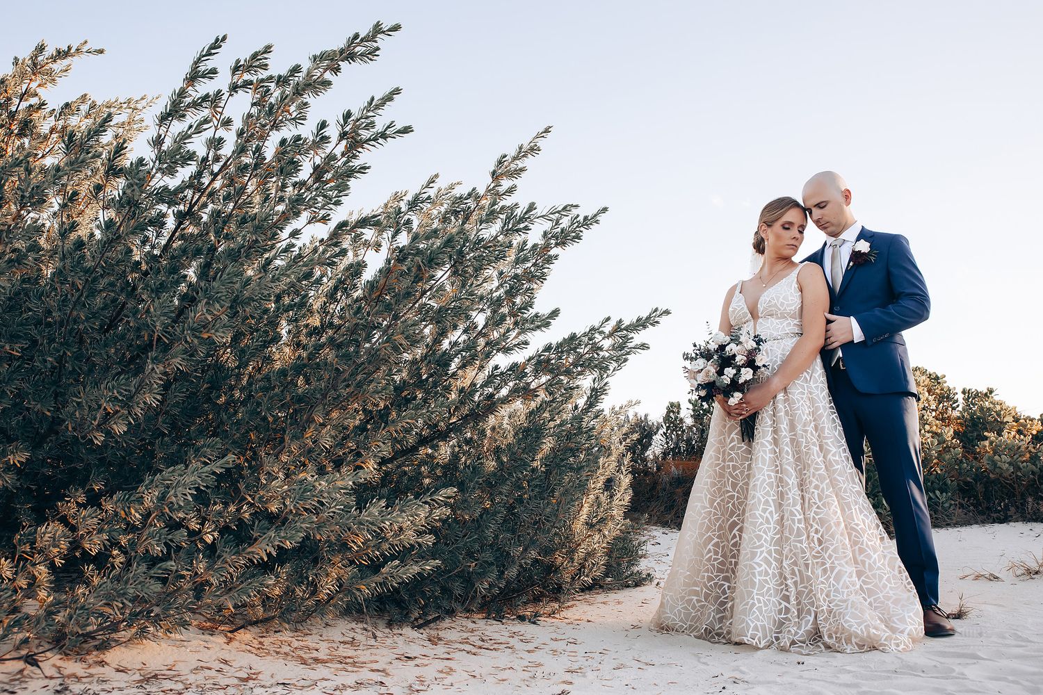 A bride and groom posing for a portrait in a natural setting.