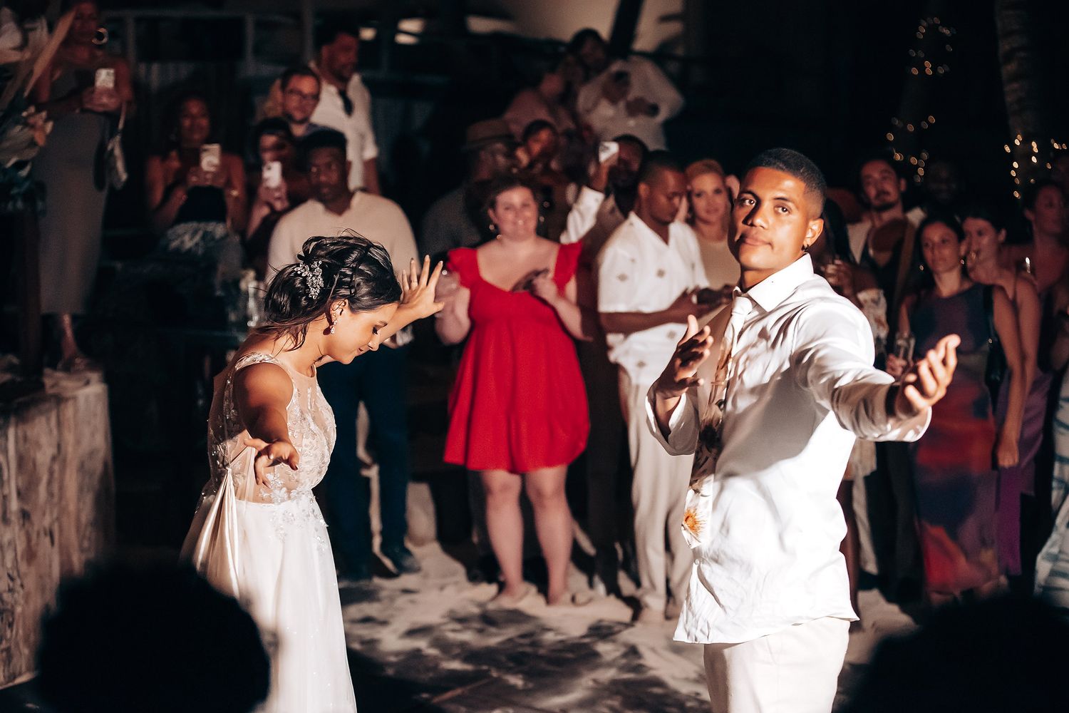 Wedding reception dance floor with guests celebrating under string lights.