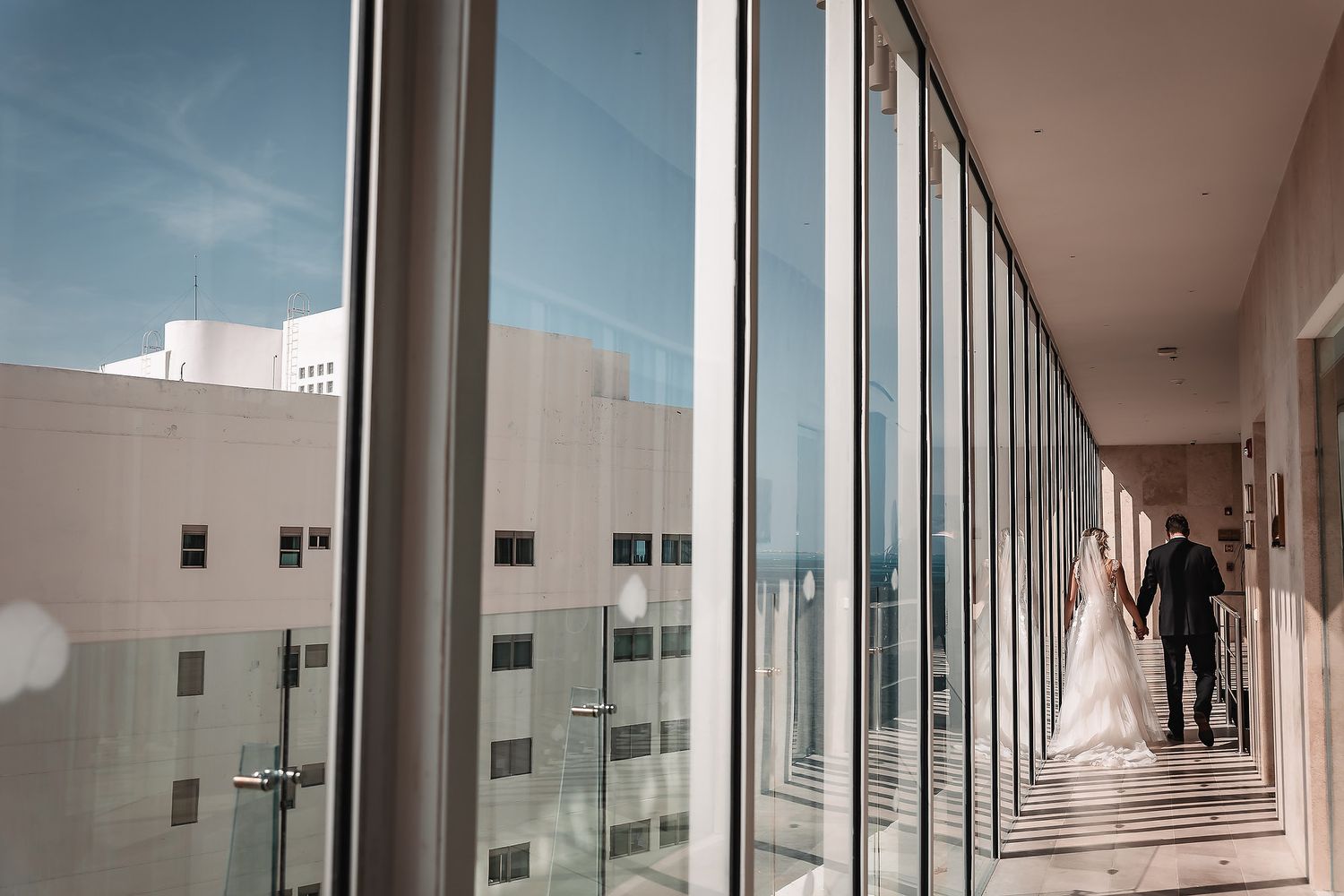 Modern architectural hallway with glass windows and geometric lines creating dramatic perspective.