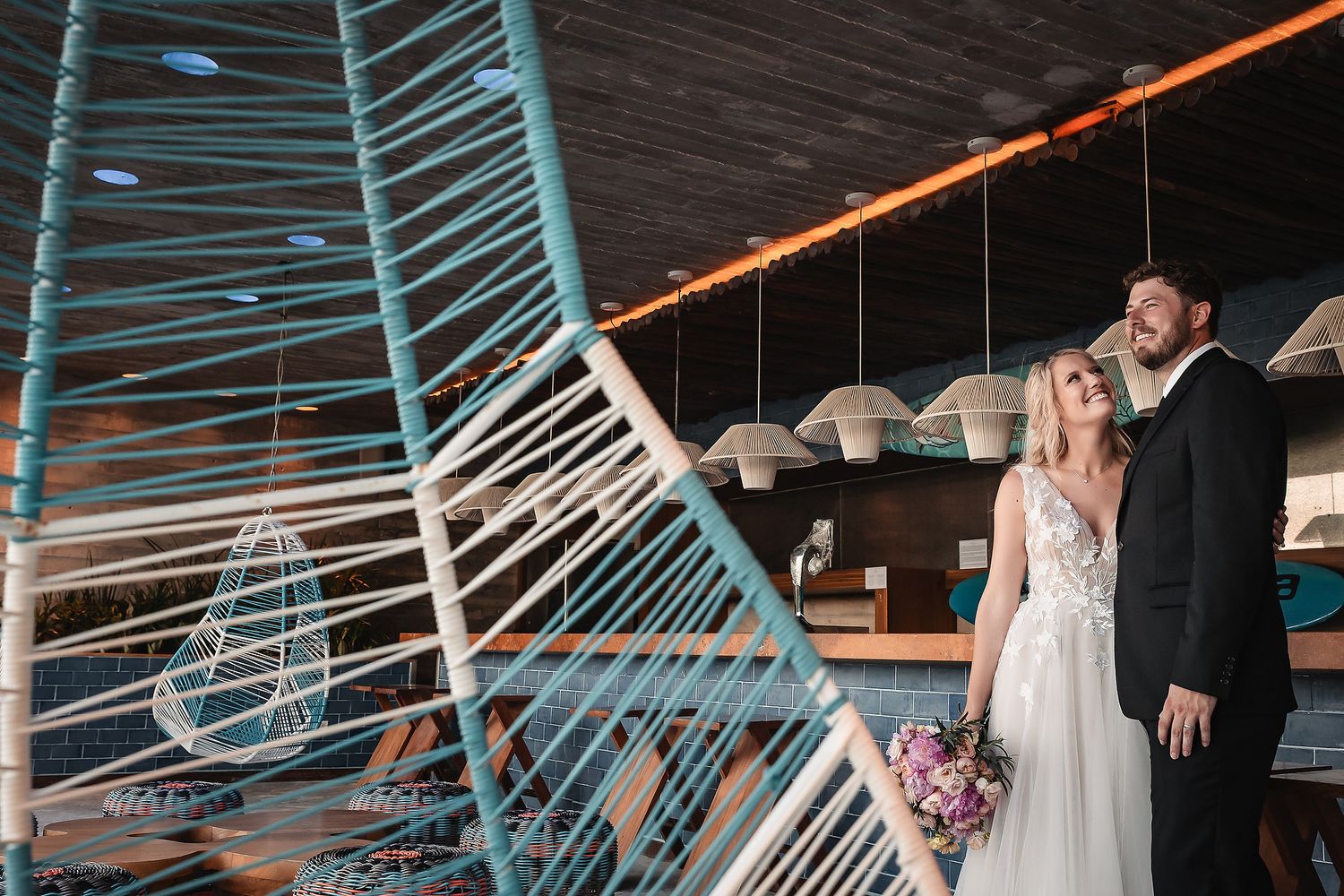Wedding couple dancing under modern architectural lighting with blue and orange hues.
