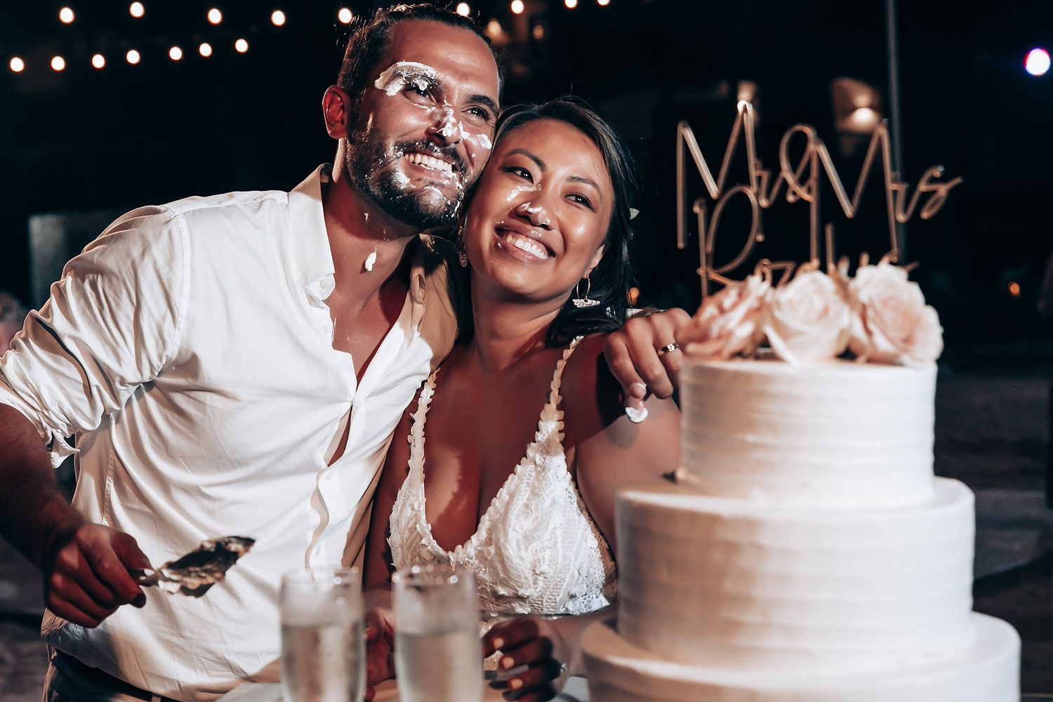 Wedding couple sharing a moment with their white tiered cake at the reception.