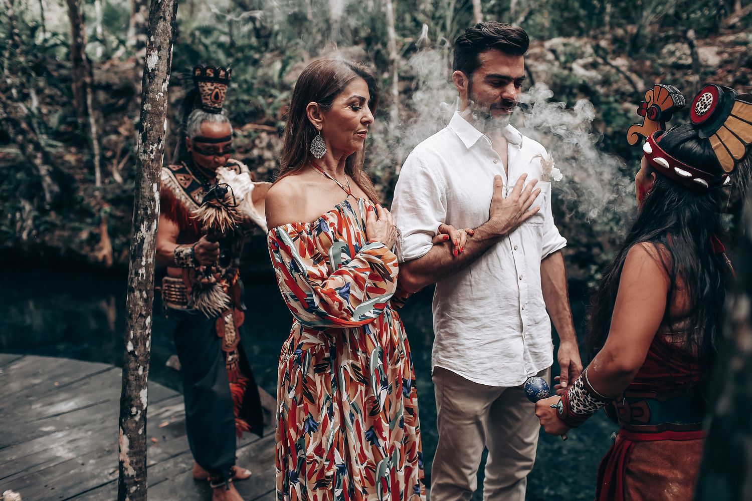 A couple shares romantic moments in a forest setting during an outdoor engagement photo session.