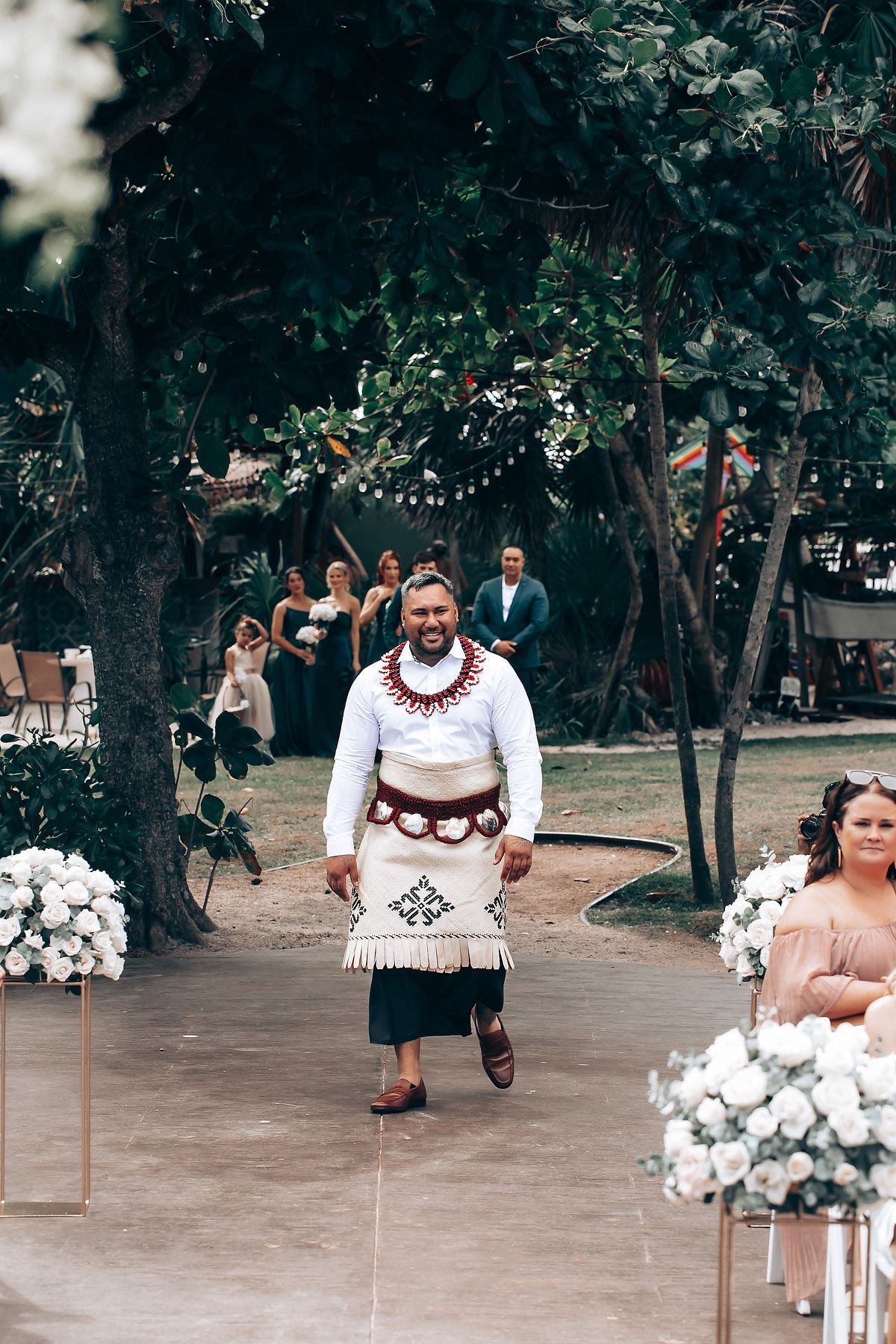 Outdoor wedding ceremony setup with white floral arrangements and wooden chairs.