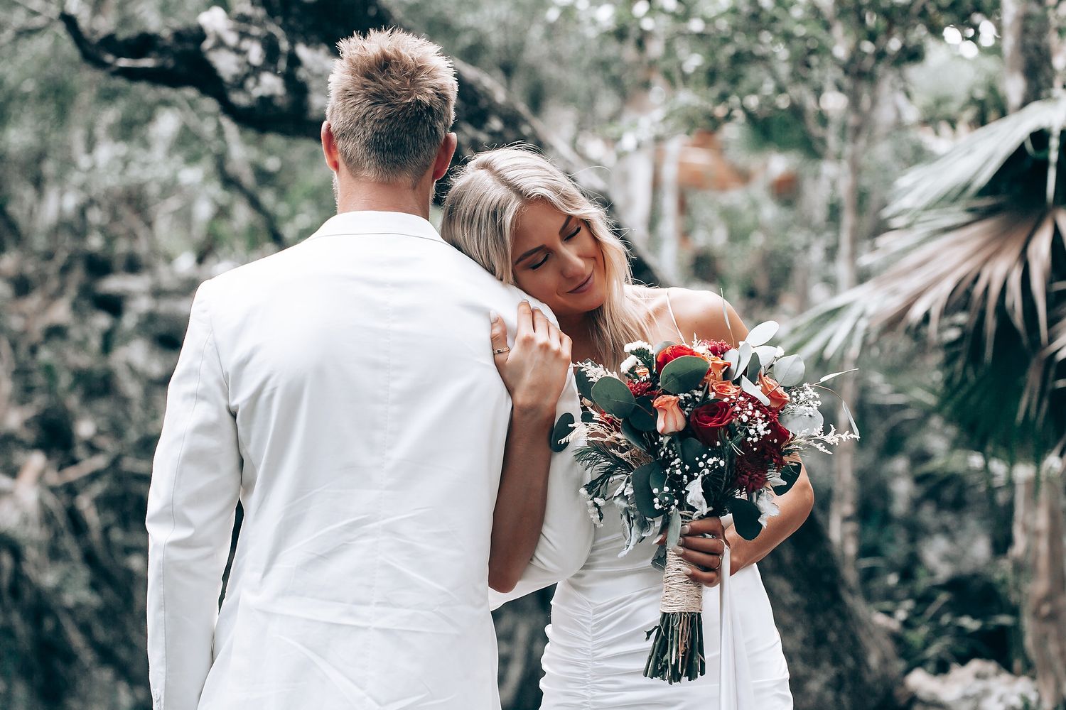 An intimate wedding moment captured in a wooded outdoor setting.