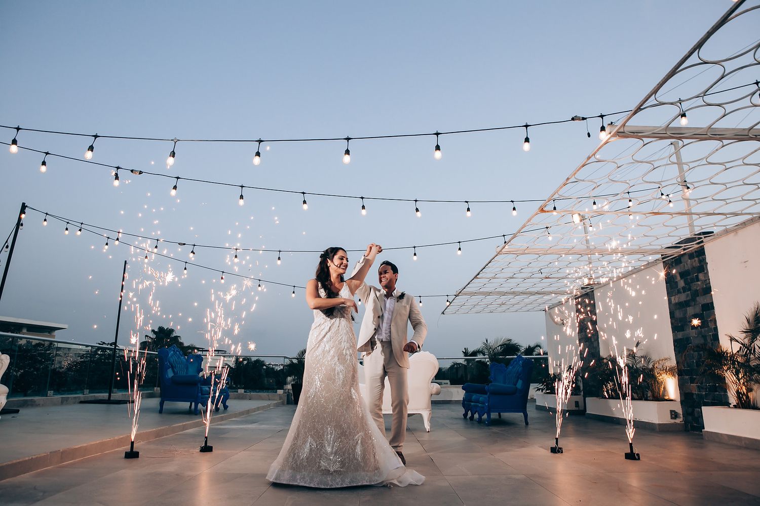 Wedding reception under string lights at dusk with sparklers creating magical atmosphere.
