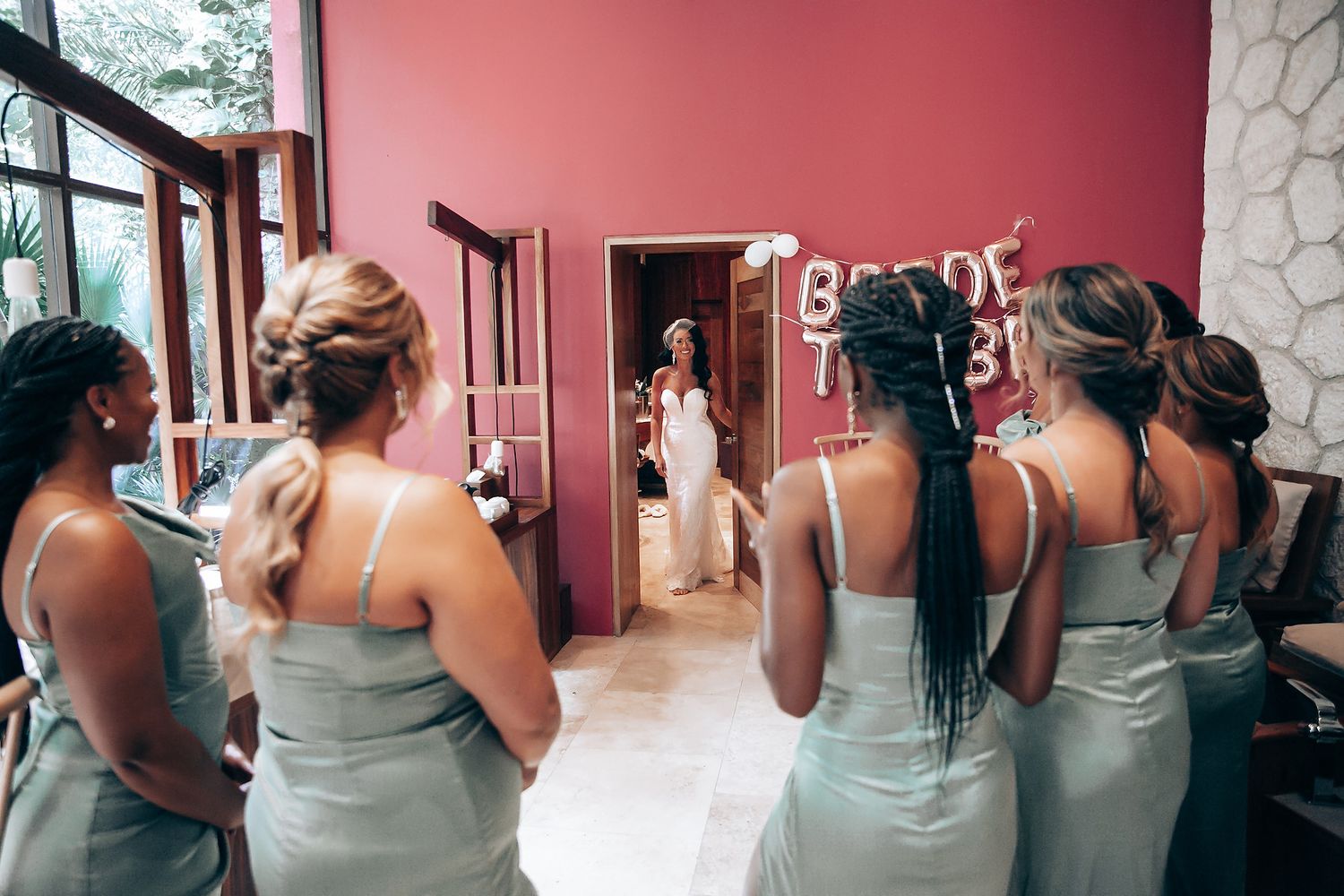 Bridesmaids in matching sage green dresses lined up for photos.