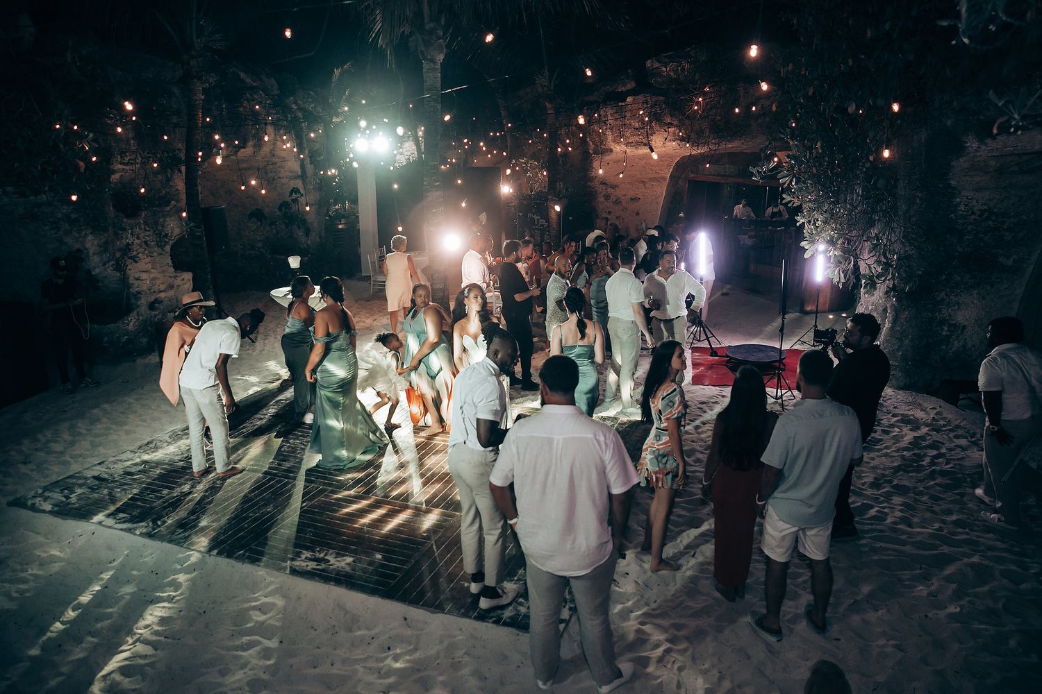 Night wedding reception with guests dancing under twinkling lights and stars.