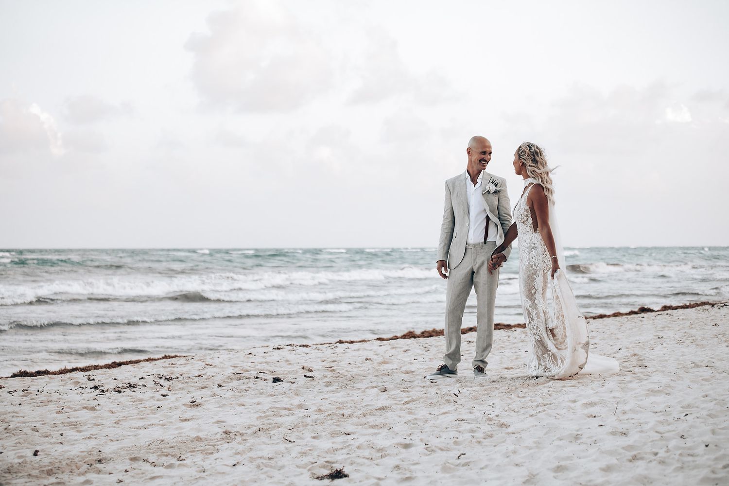 Couple walking along shoreline during beach wedding photoshoot.