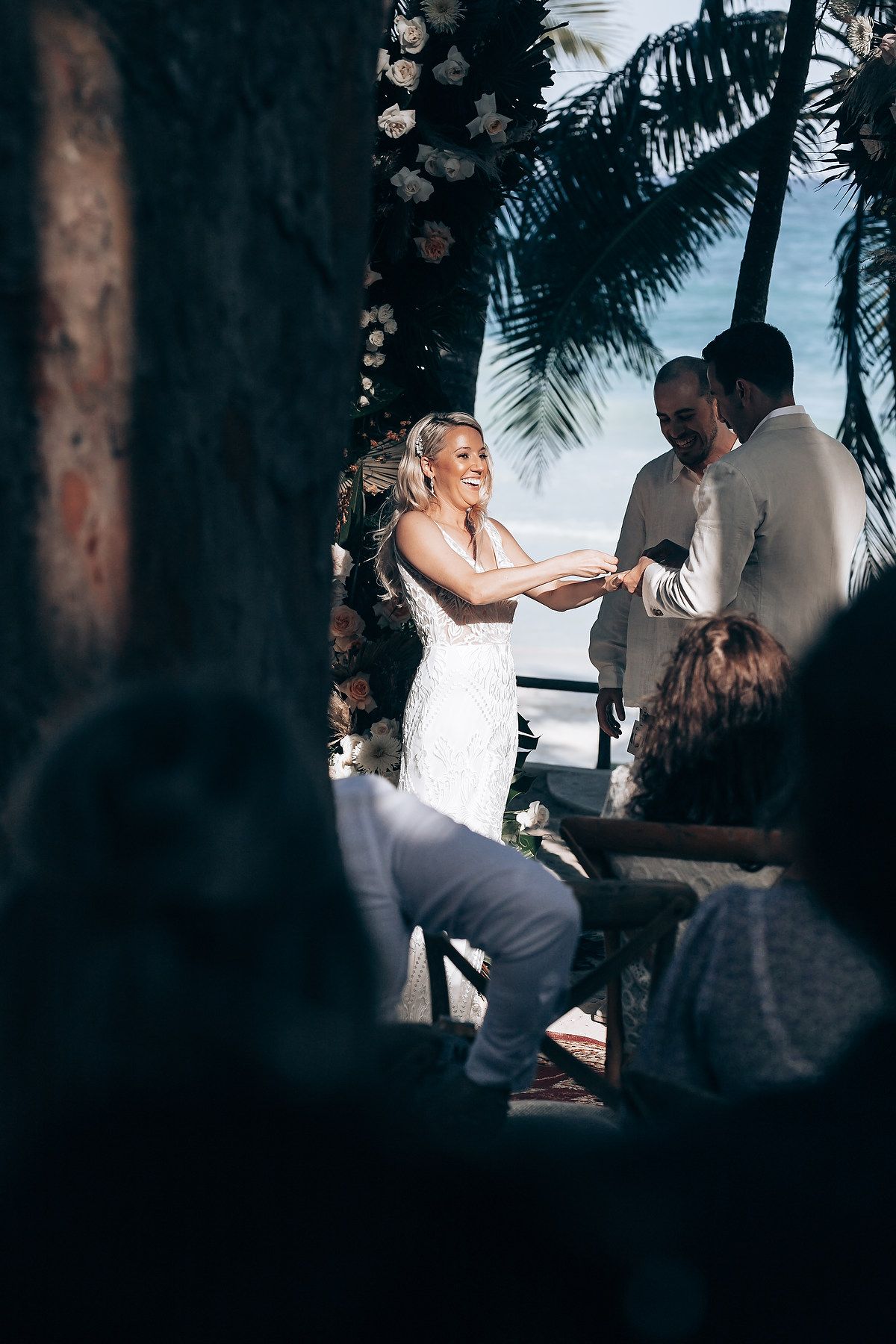 Beachside wedding ceremony under palm trees with soft natural lighting.