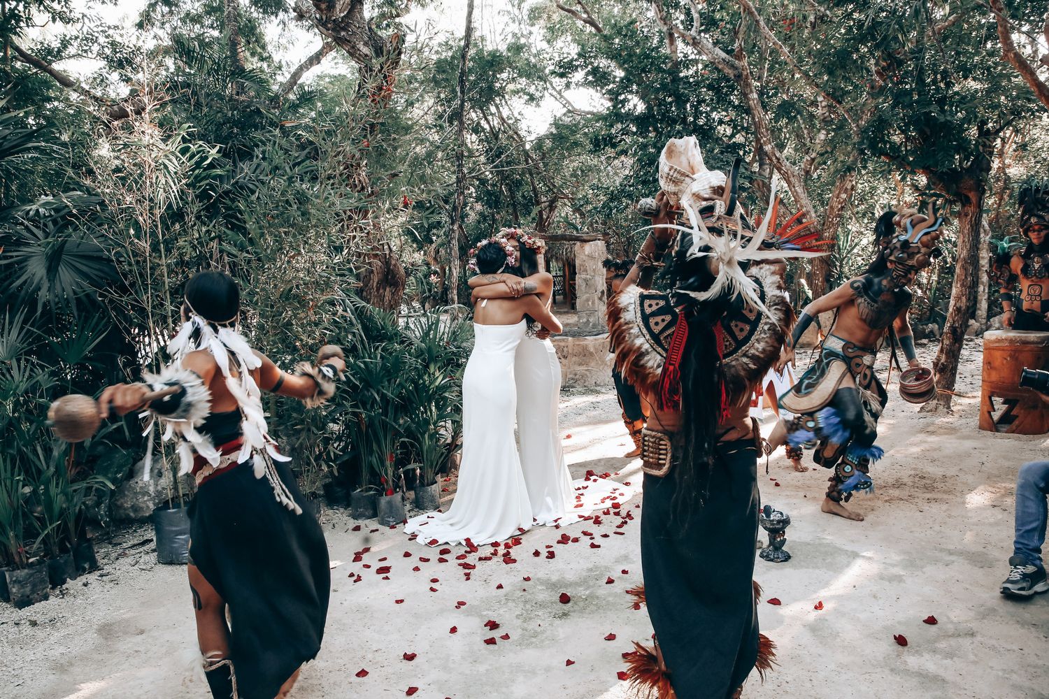 Rose petals line a pathway during an intimate ceremony in a tropical forest setting.