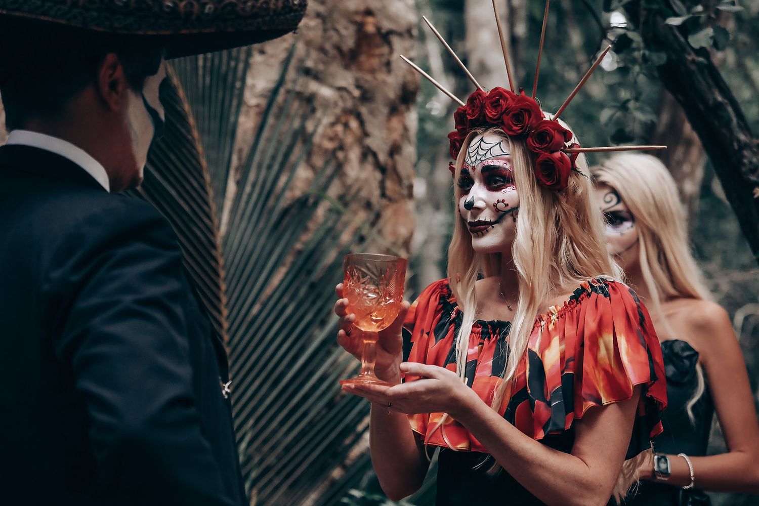 A romantic scene with sugar skull makeup and red accents against a forest backdrop.