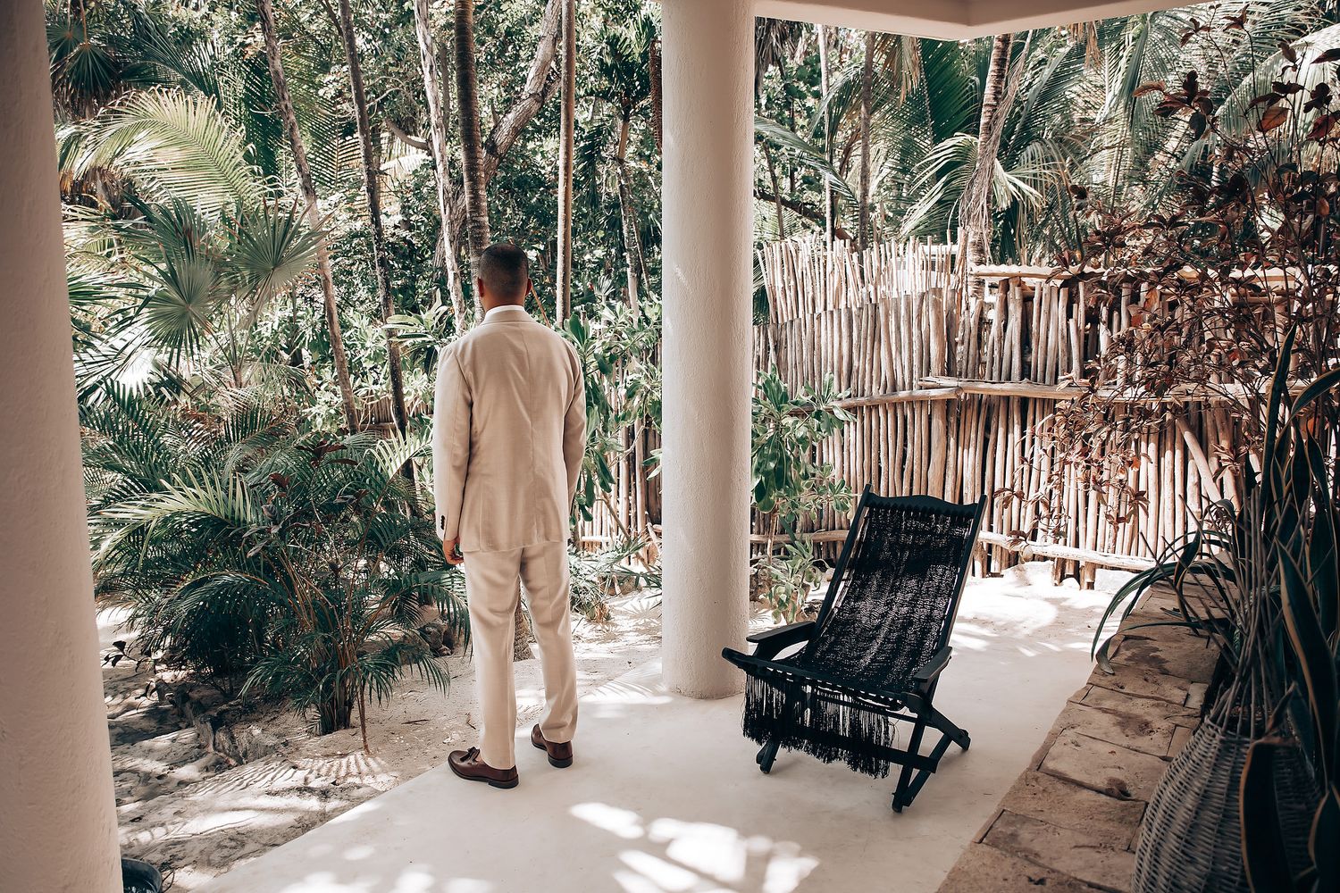 A covered patio area with rocking chairs and palm trees creates a tropical resort atmosphere.